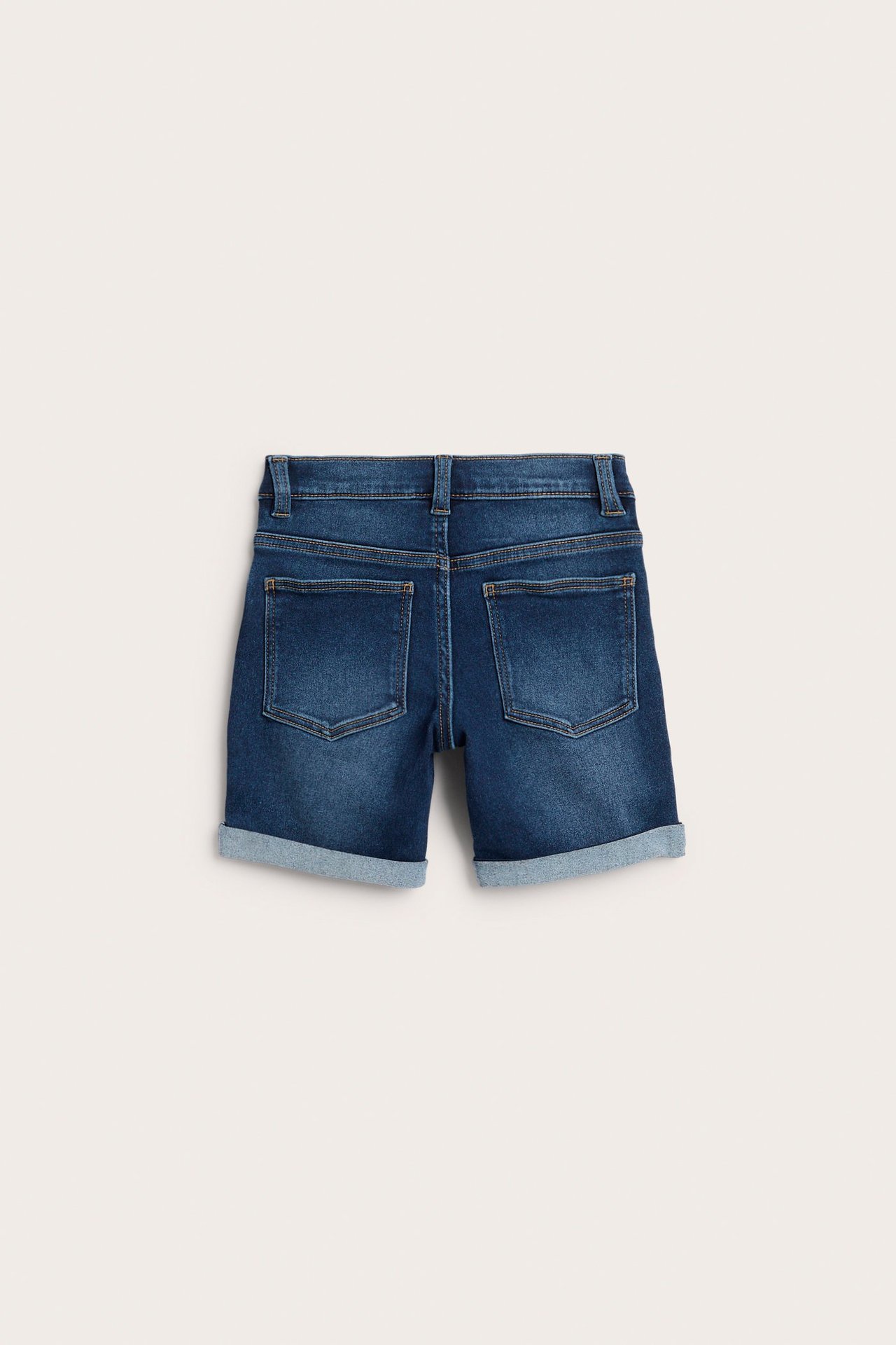Mörkblå enfärgade jeansshorts för barn, bakifrån, med uppvikta benslut och bakfickor.