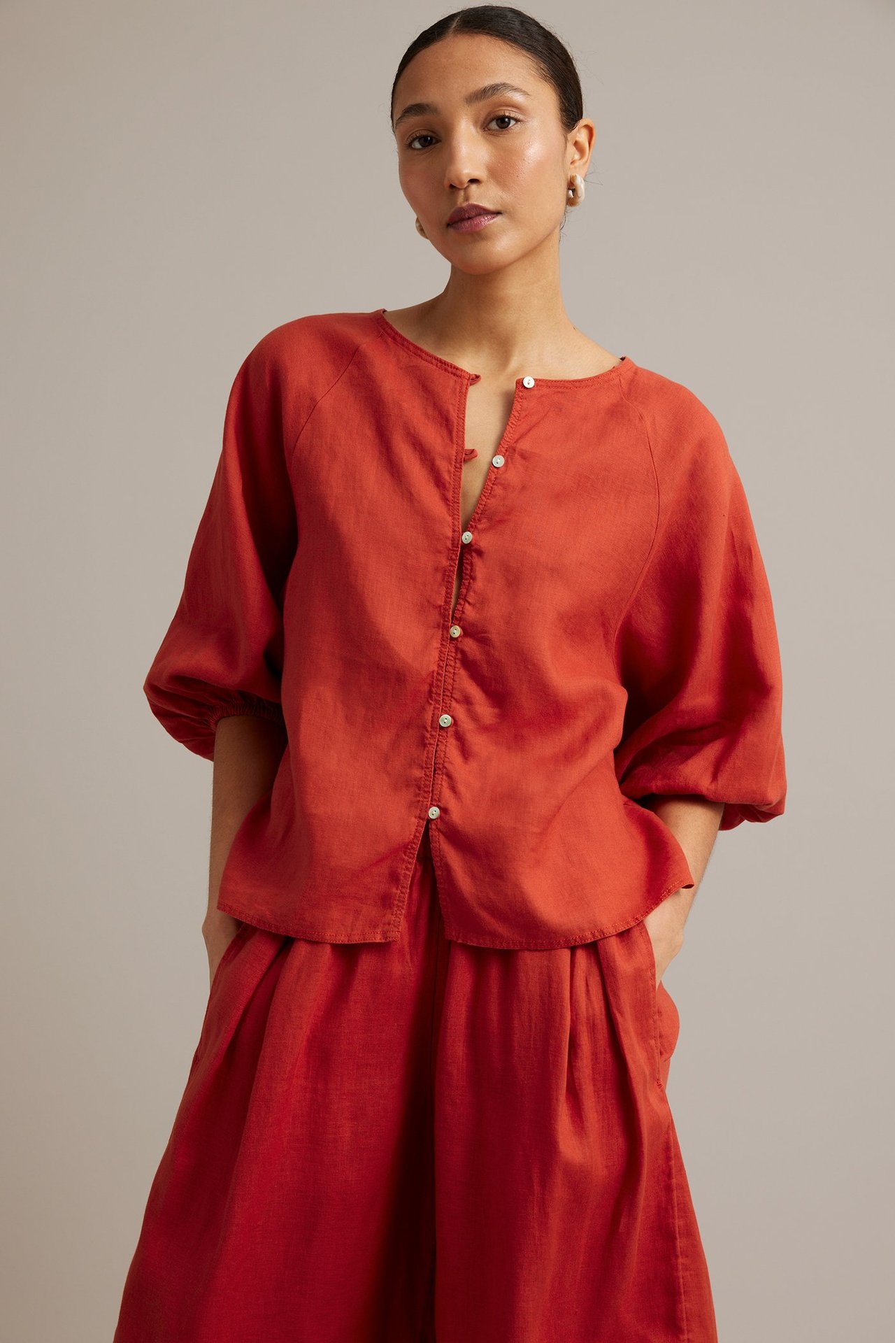Frontbilde av en kvinne i rød linbluse med vide raglanermer, stylet med matchende bukser.