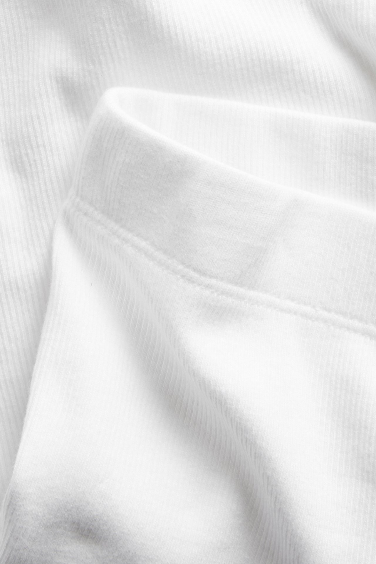 Närbild av vita ribbade cykelshorts, visar det mjuka bomulls-/elastan-tyget och den elastiska linningen.