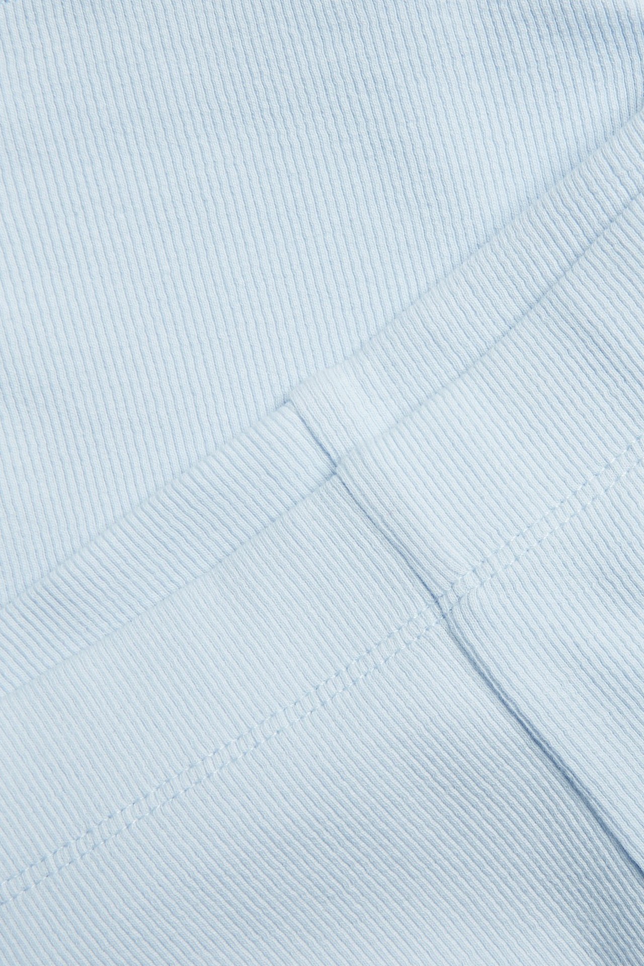 Zbliżenie jasnoniebieskich prążkowanych szortów rowerowych z widocznymi szwami.