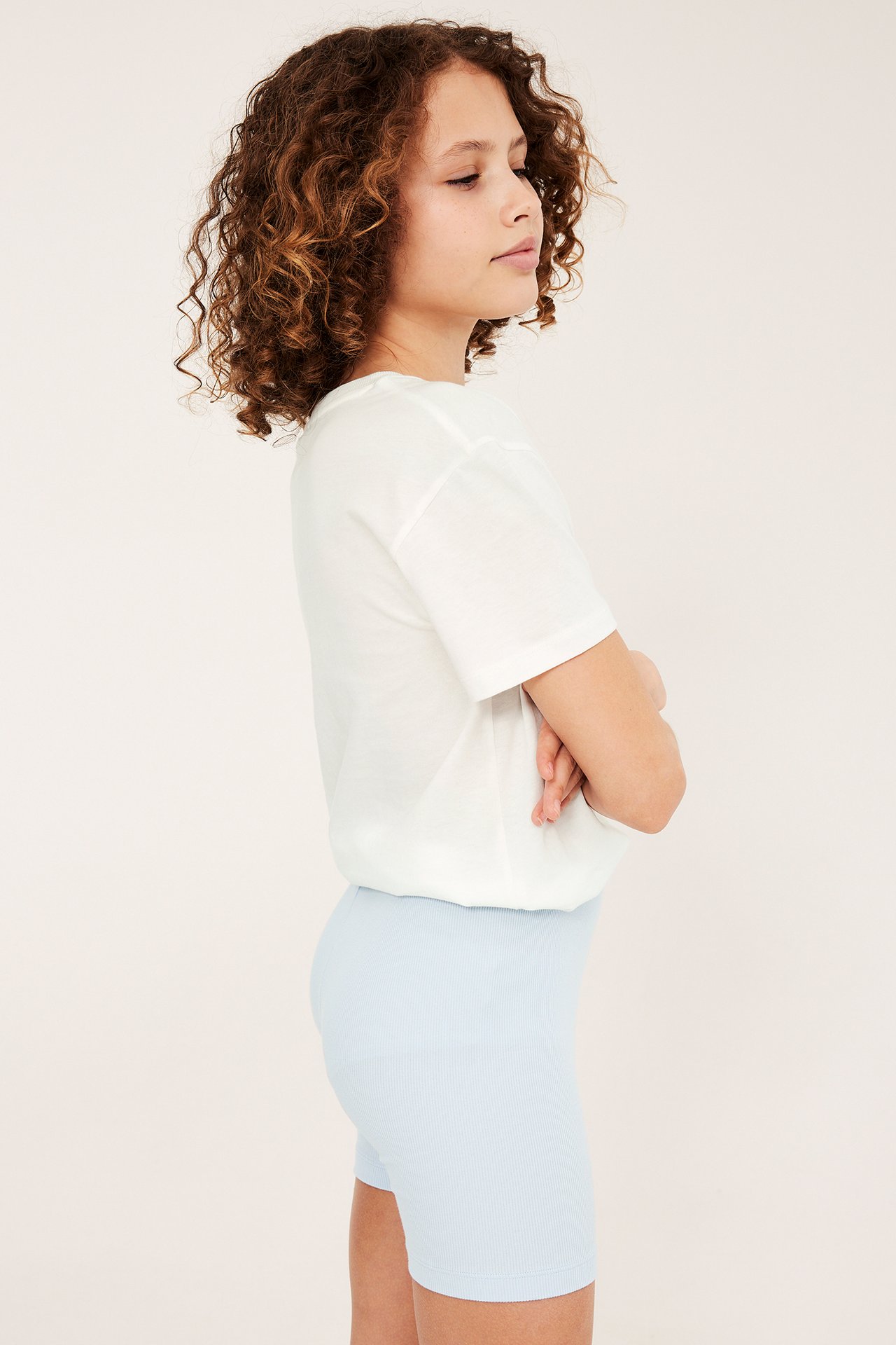 Sidebilde av et barn i lyseblå ribbestrikkede sykkelshorts og en hvit t-skjorte.
