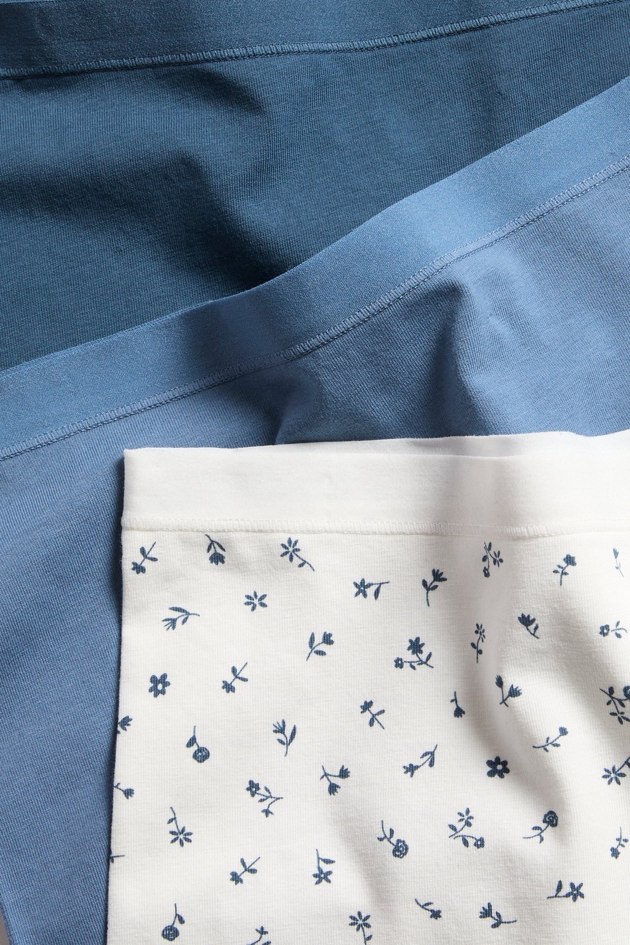 Närbild av vita mönstrade damboxertrosor med blå blommor och enfärgade blå boxertrosor.