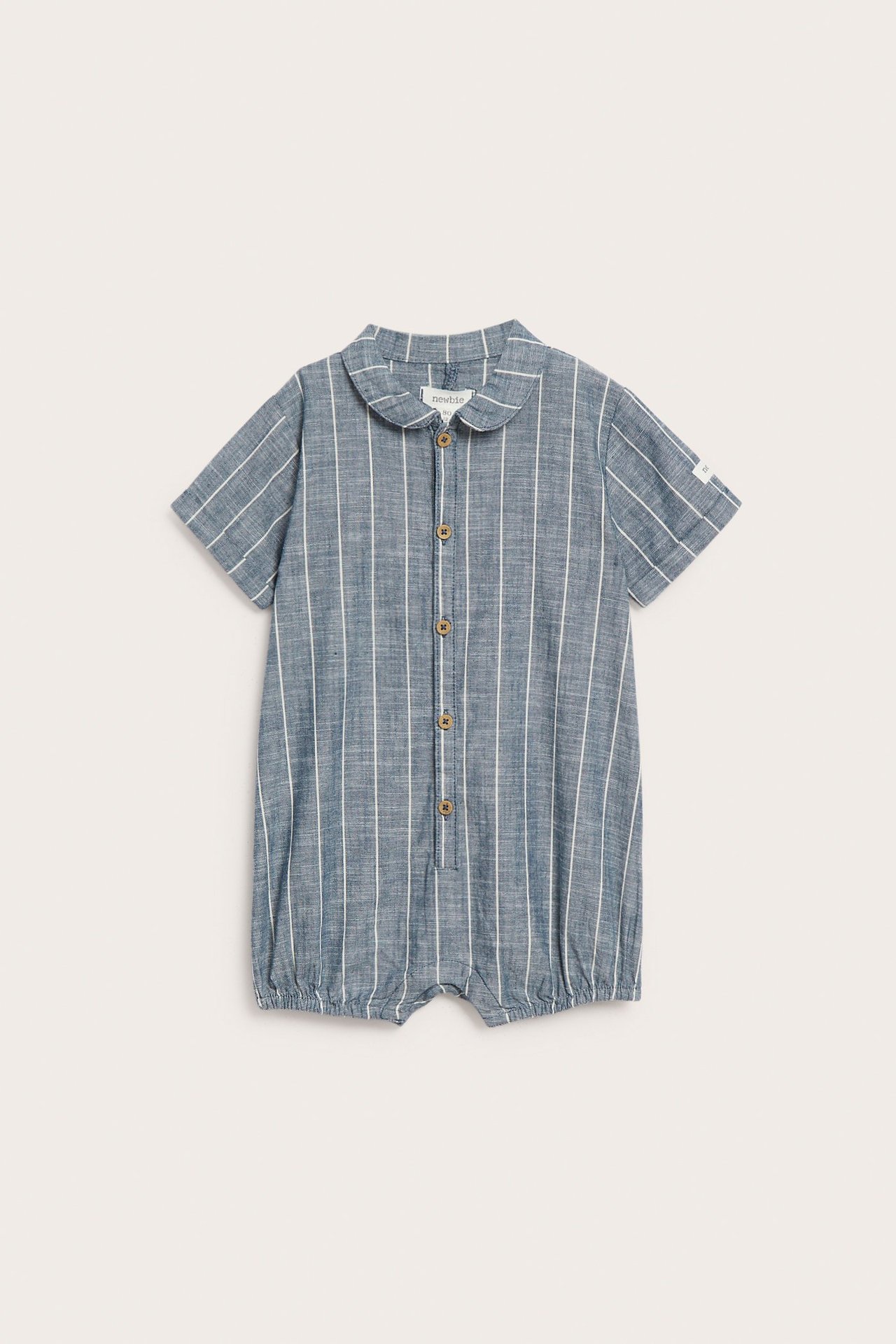 Widok z przodu niebieskiego, bawełnianego rampersa dla niemowląt w paski, z kołnierzykiem i guzikami.