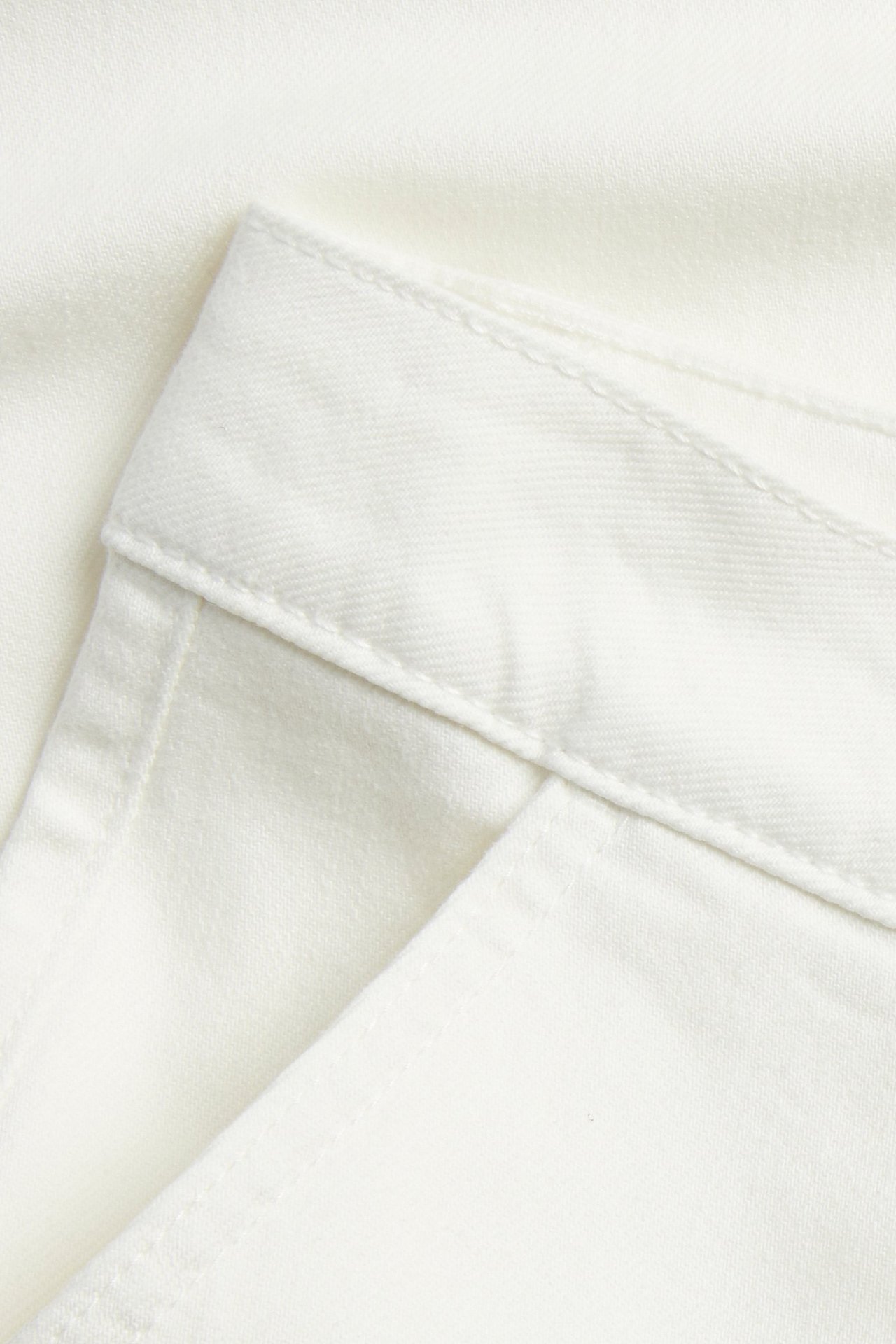 Zbliżenie na off-white spodnie twillowe, pokazujące pas i otwór przedniej kieszeni.