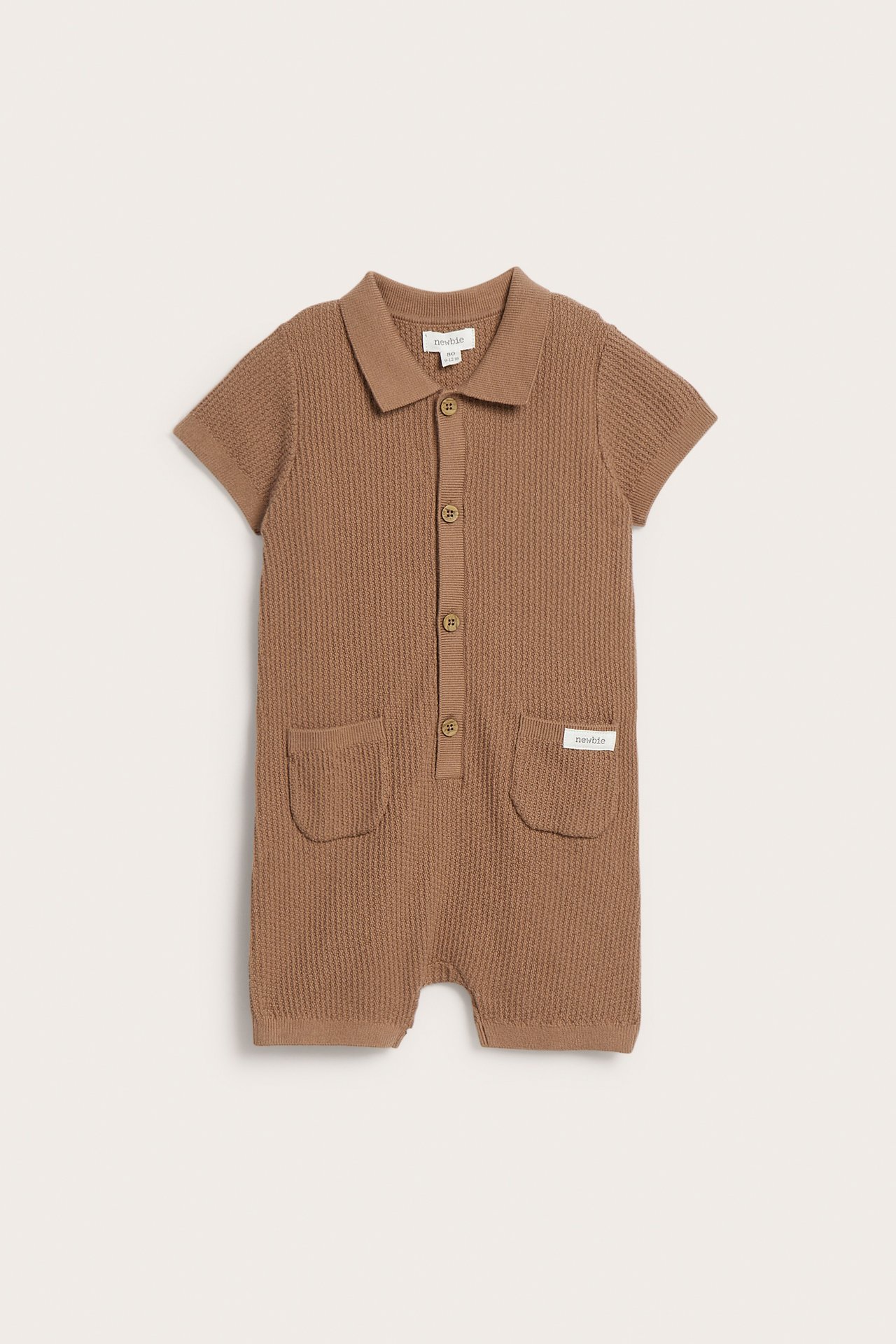 Framifrån, brun finstickad bomullsromper för baby med korta ärmar, krage, knappar fram och fickor.