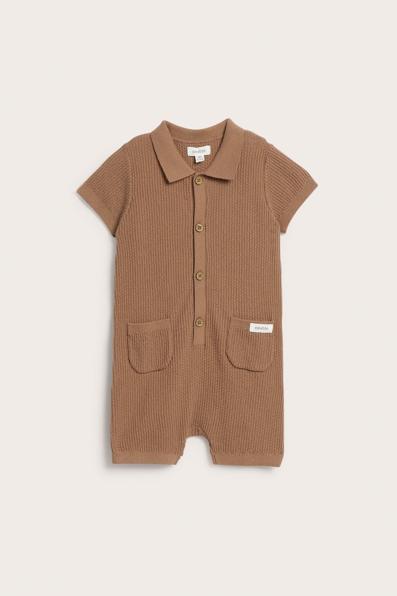 Frontvy av en brun finstickad kortärmad babyromper med krage, knappar och två fickor.
