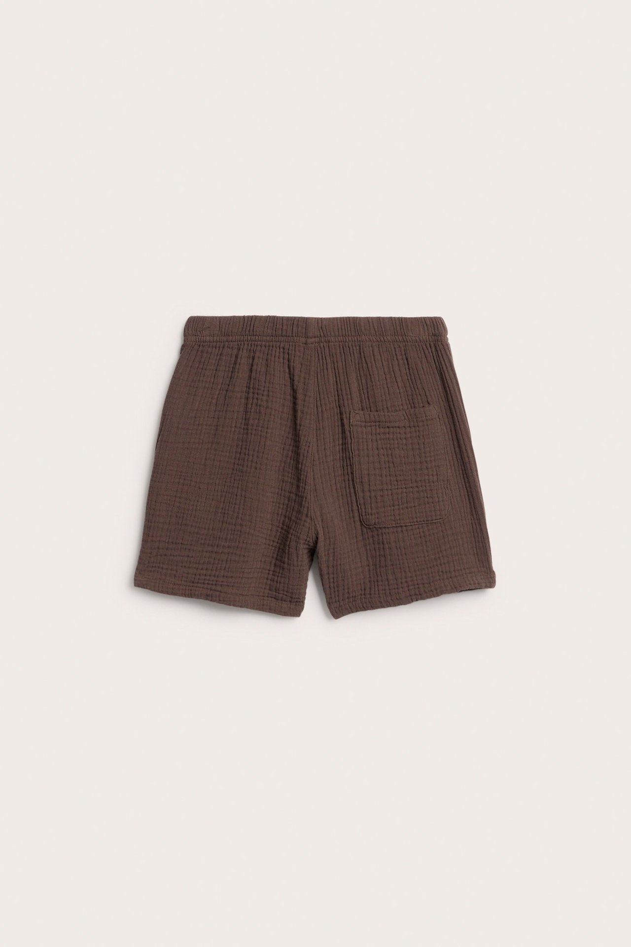 Widok z tyłu brązowych dziecięcych szortów muślinowych z elastyczną talią i jedną kieszenią.