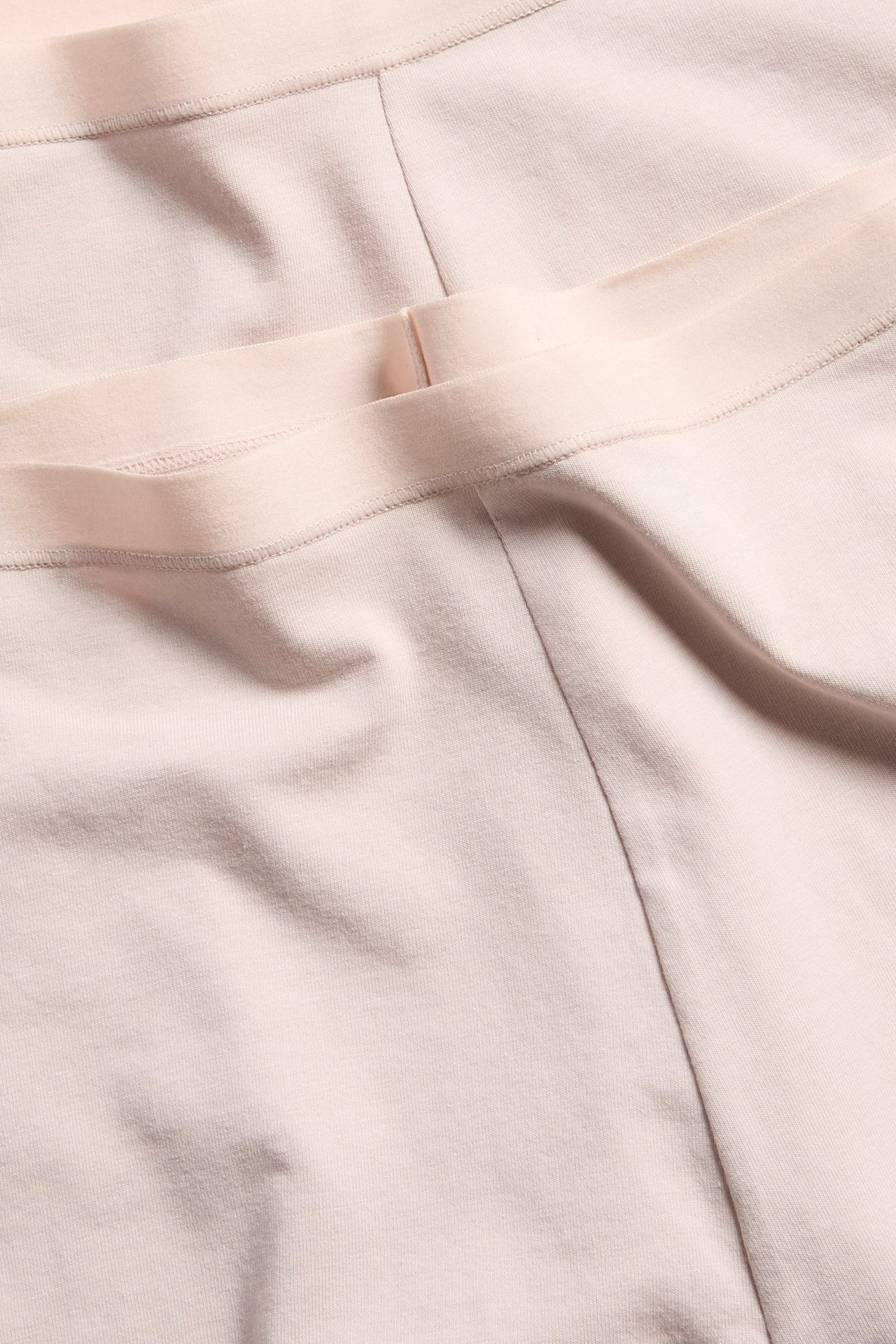 Nærbilde av to par lyserosa bomullsshorts med myke elastiske midjebånd.