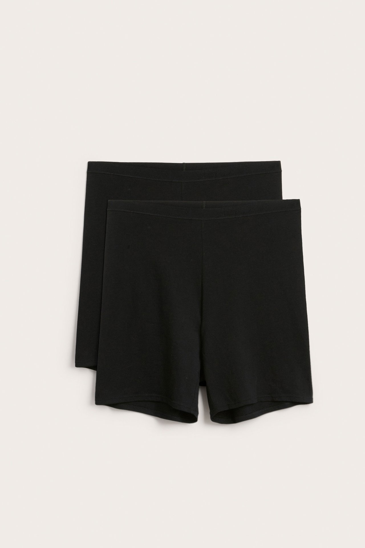 Frontvisning av to par svarte høymidjede bomullsshorts med myk elastisk linning.