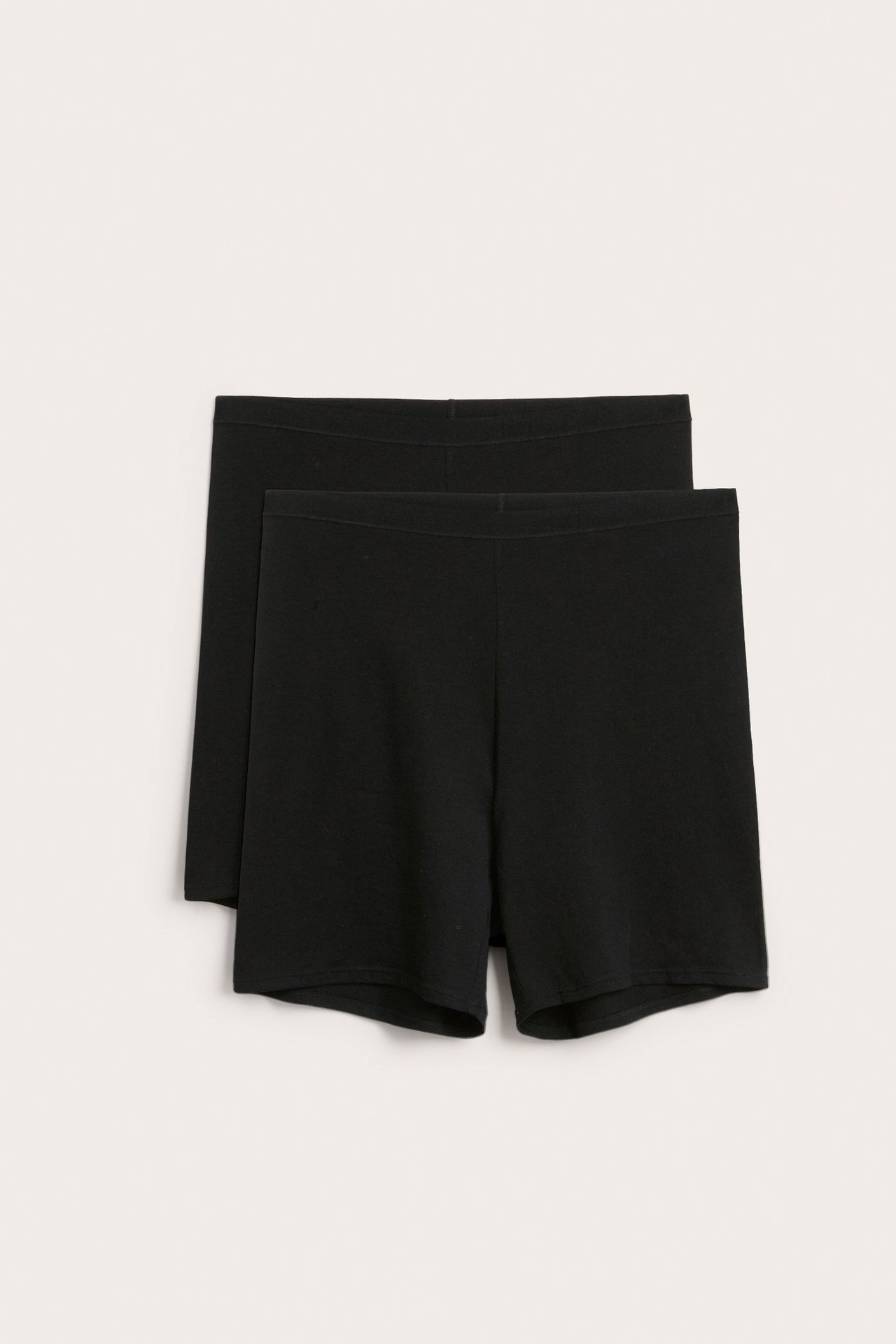 Frontvisning av to par svarte høymidjede bomullsshorts med myk elastisk linning.