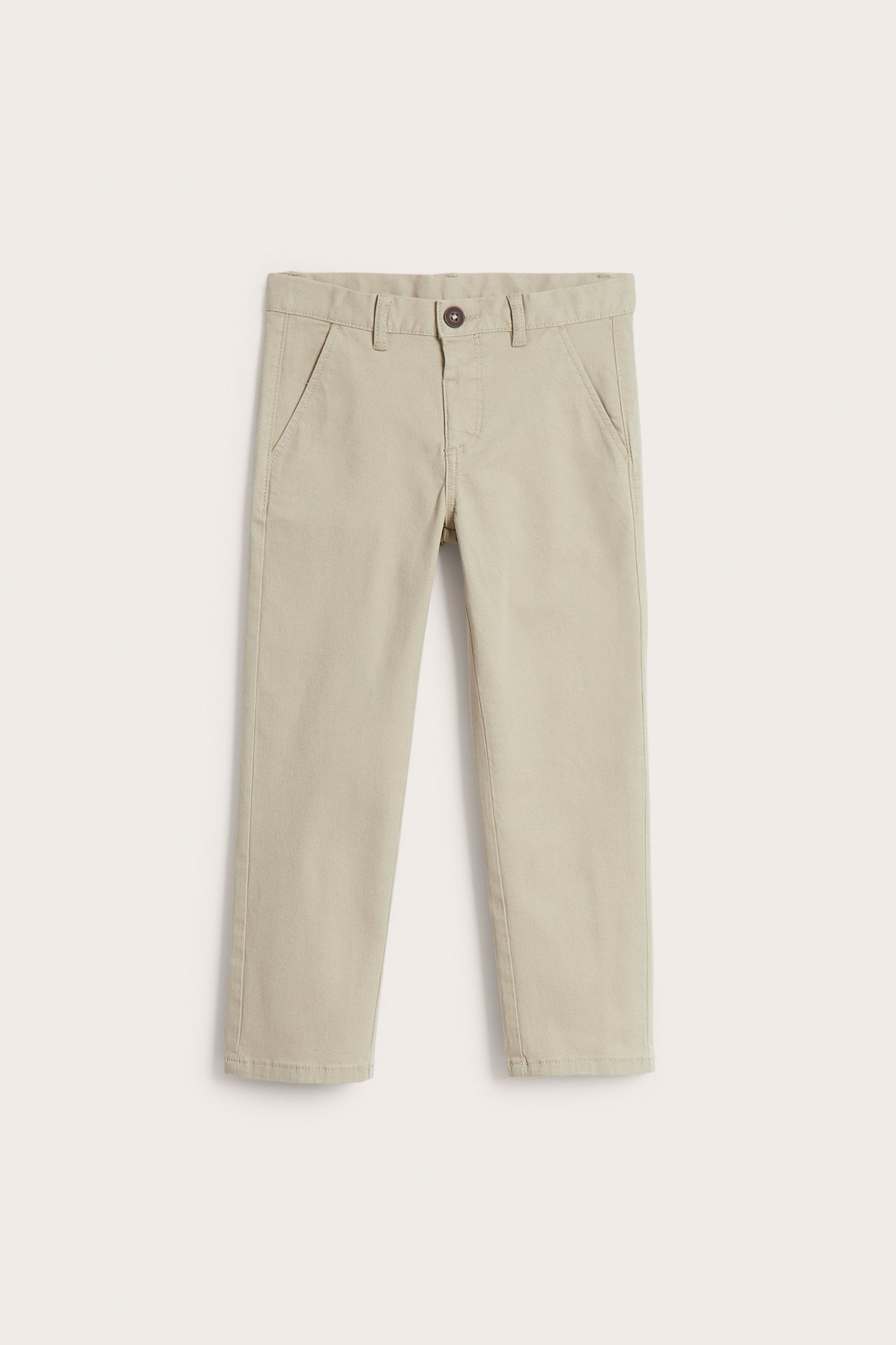 Edestä näkymä beigestä lasten chinohousuista joustavasta puuvillatvillistä napilla ja sivutaskuilla.