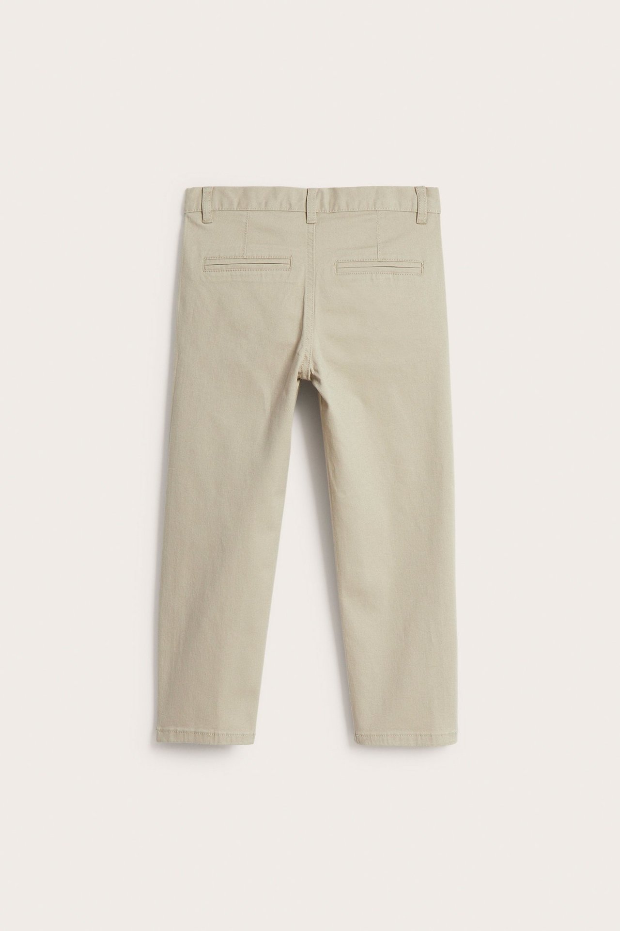 Widok z tyłu beżowych dziecięcych chinosów z bawełnianego twillu z tylnymi kieszeniami.