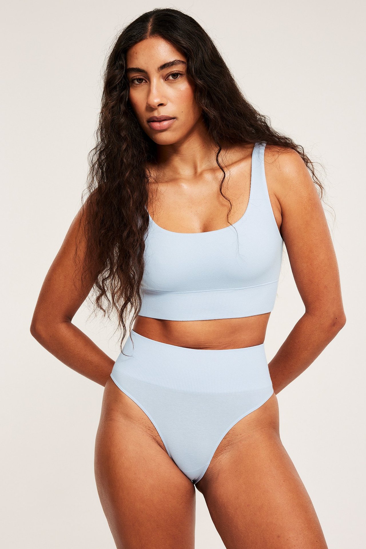 Forfra, kvinne i lys blå sømløs bomullsmiks BH-topp og matchende truse med høyt liv.
