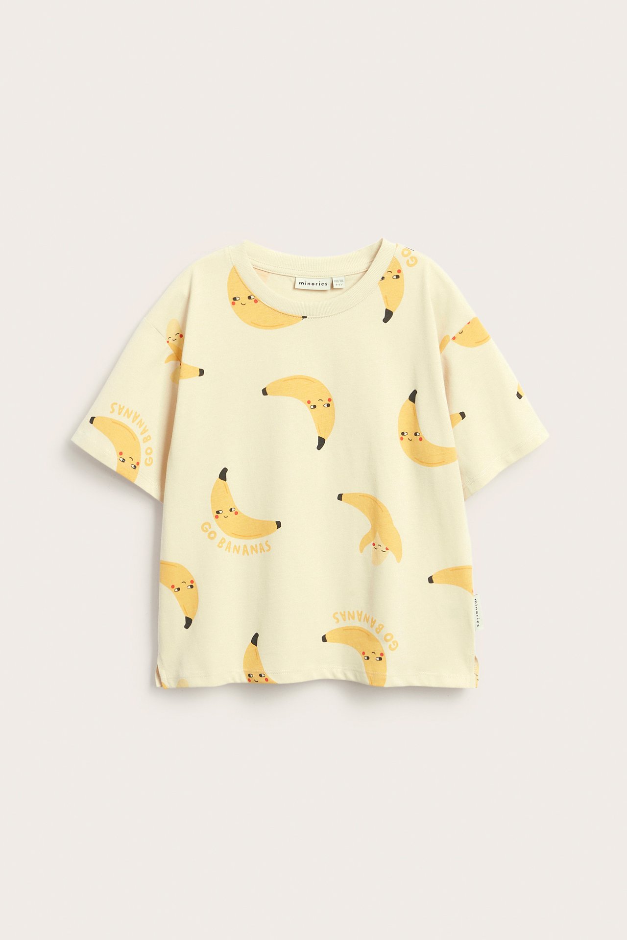 Framifrån, barnens beige bomulls-t-shirt med glatt bananmönster och texten "Go Bananas".