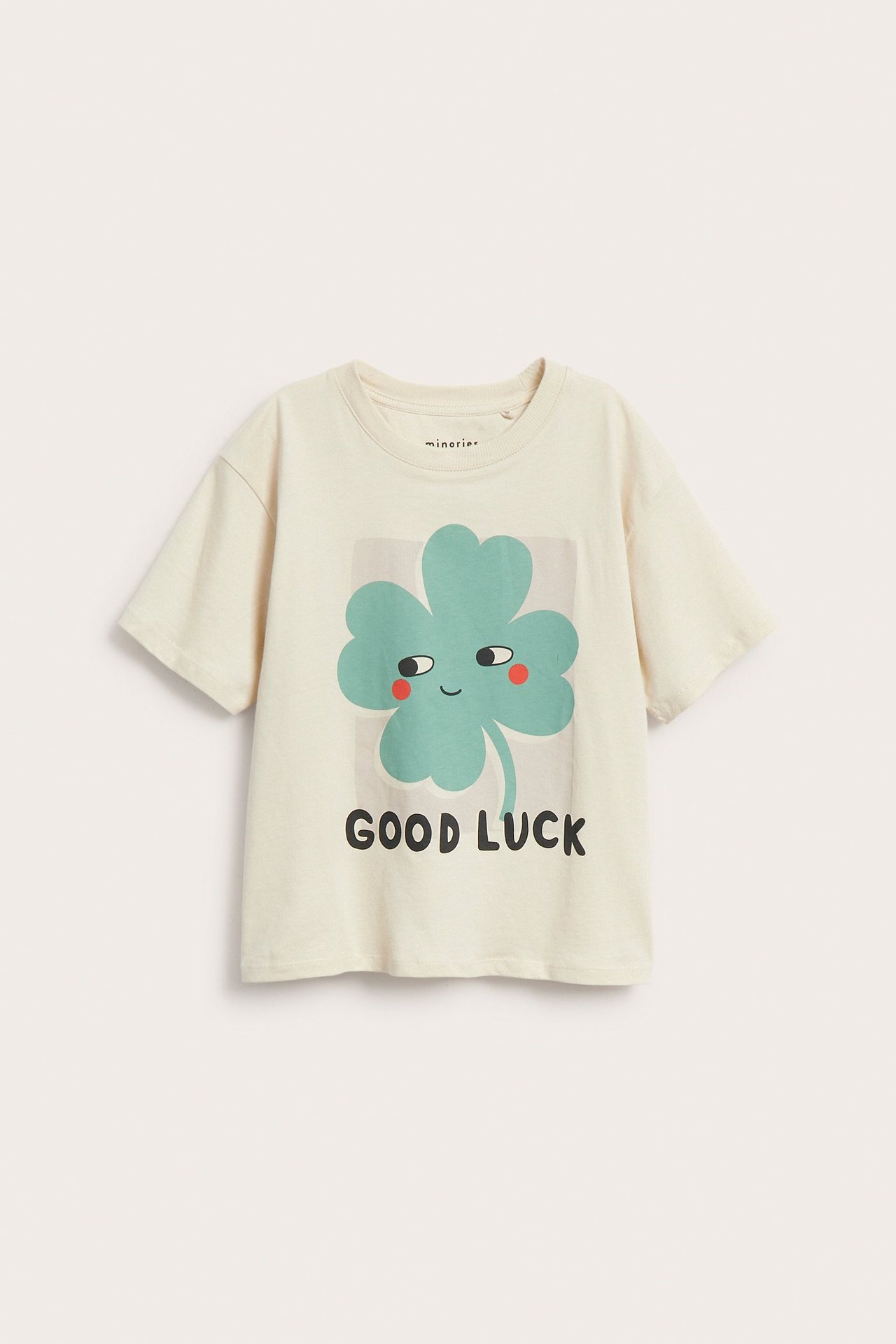 Widok z przodu: Beżowy t-shirt z krótkim rękawem z zieloną koniczyną i napisem „GOOD LUCK”.