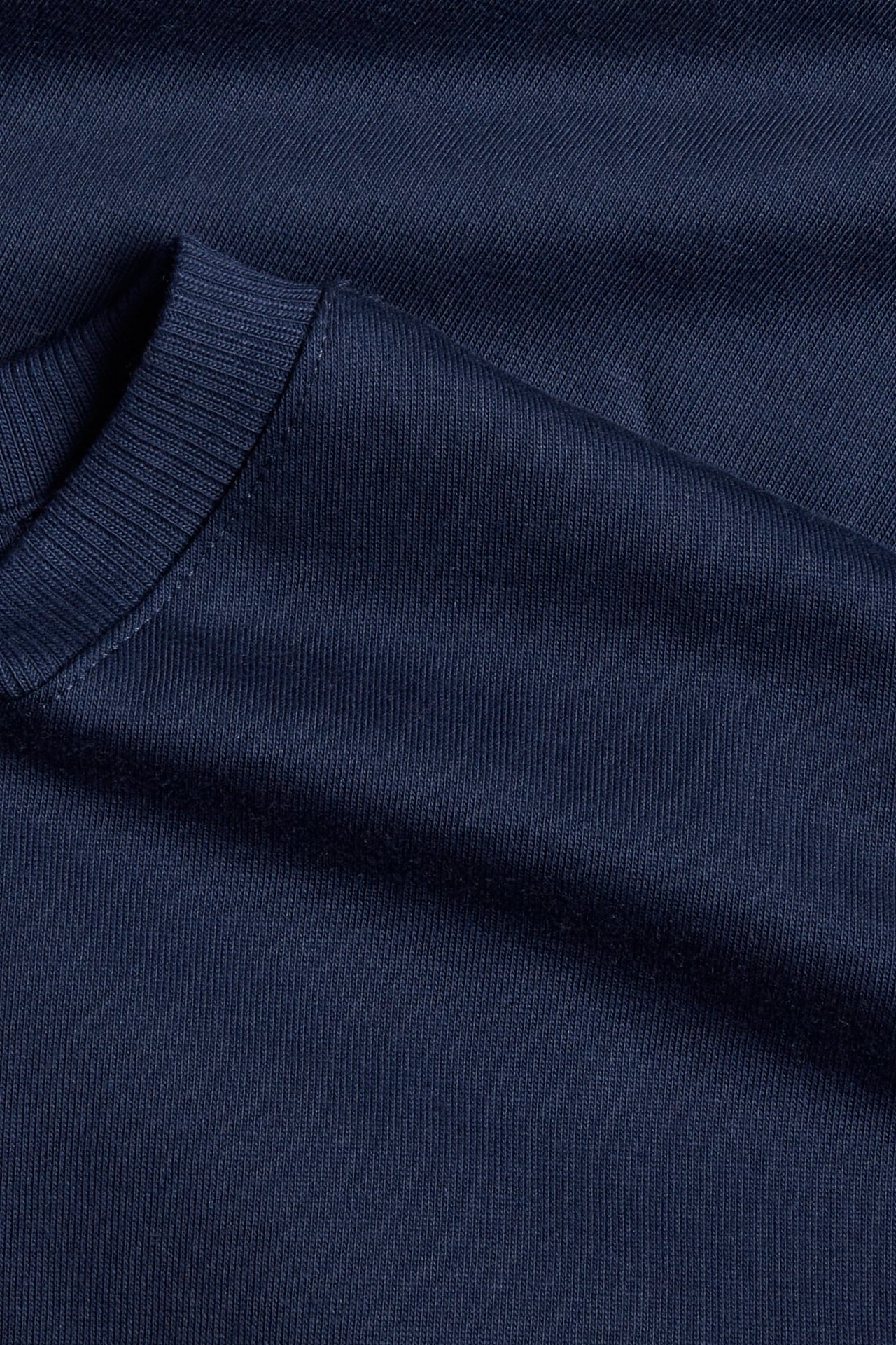 Zbliżenie na gładki granatowy bawełniany t-shirt z prążkowanym okrągłym dekoltem.