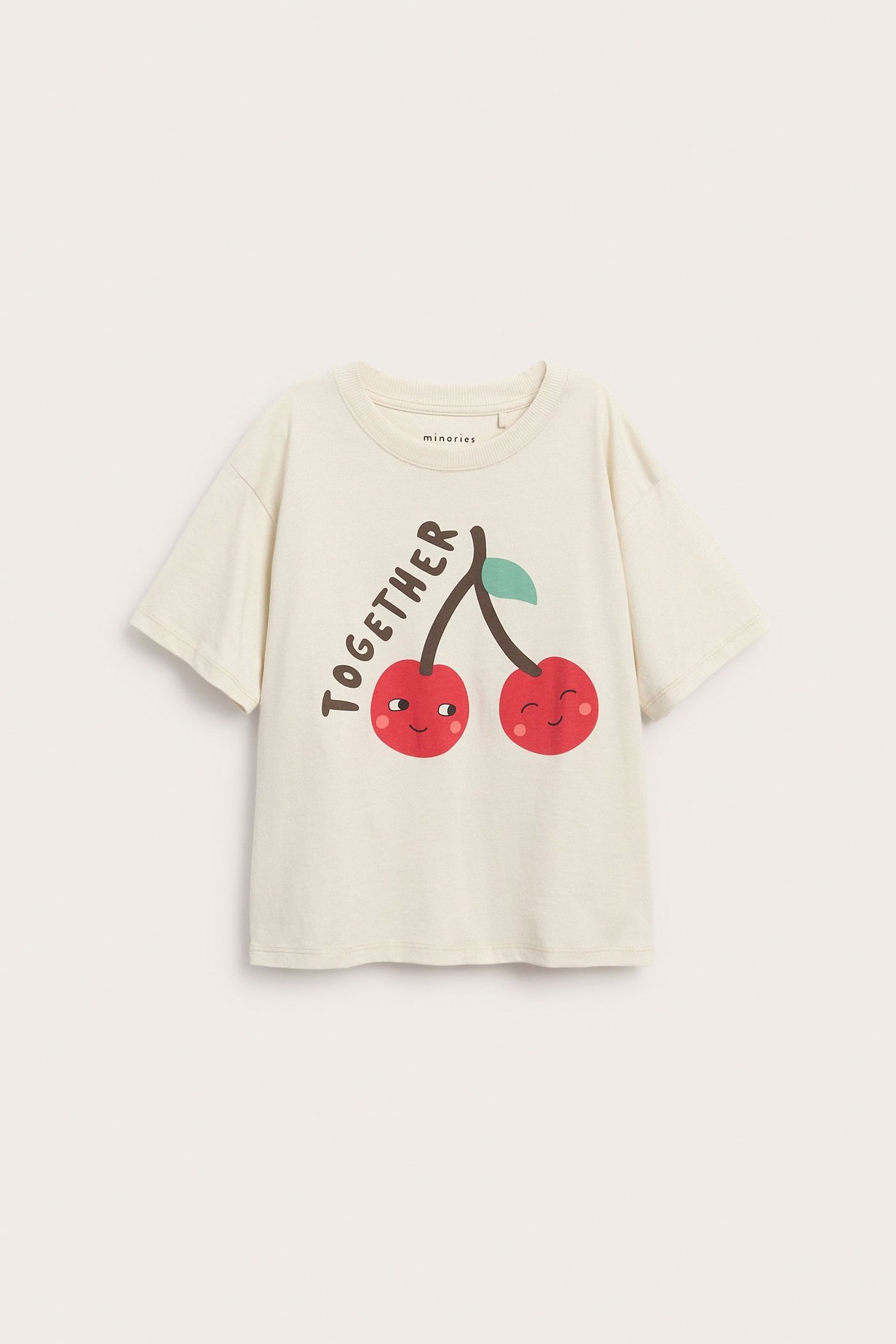 Frontvy av en ljusbeige barnt-shirt i bomull med tryck av röda, leende körsbär och texten 'TOGETHER'.