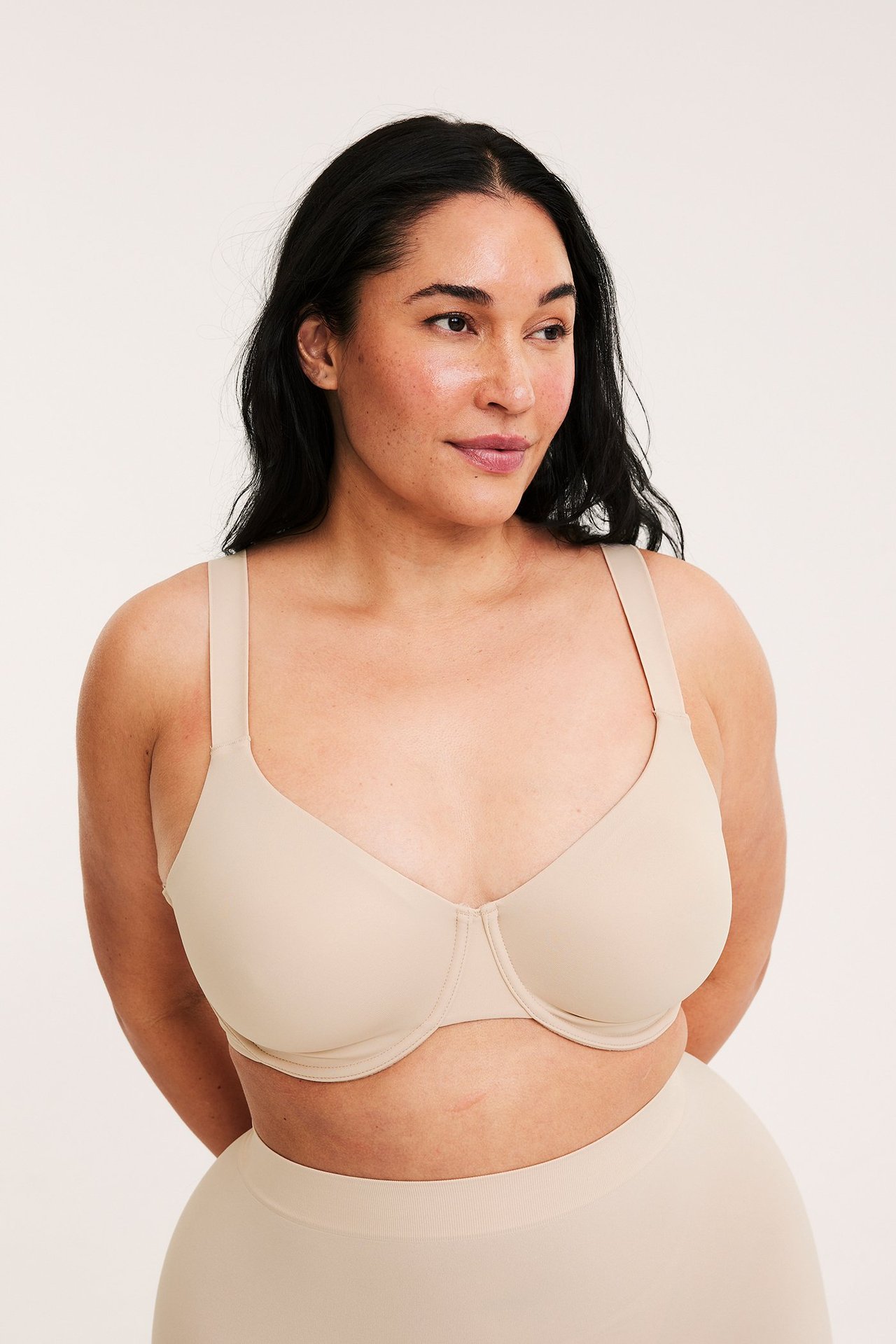 Edestäpäin nainen yllään vaaleanpunainen minimizer-kaarituki-rintaliivit ja yhteensopivat alushousut.