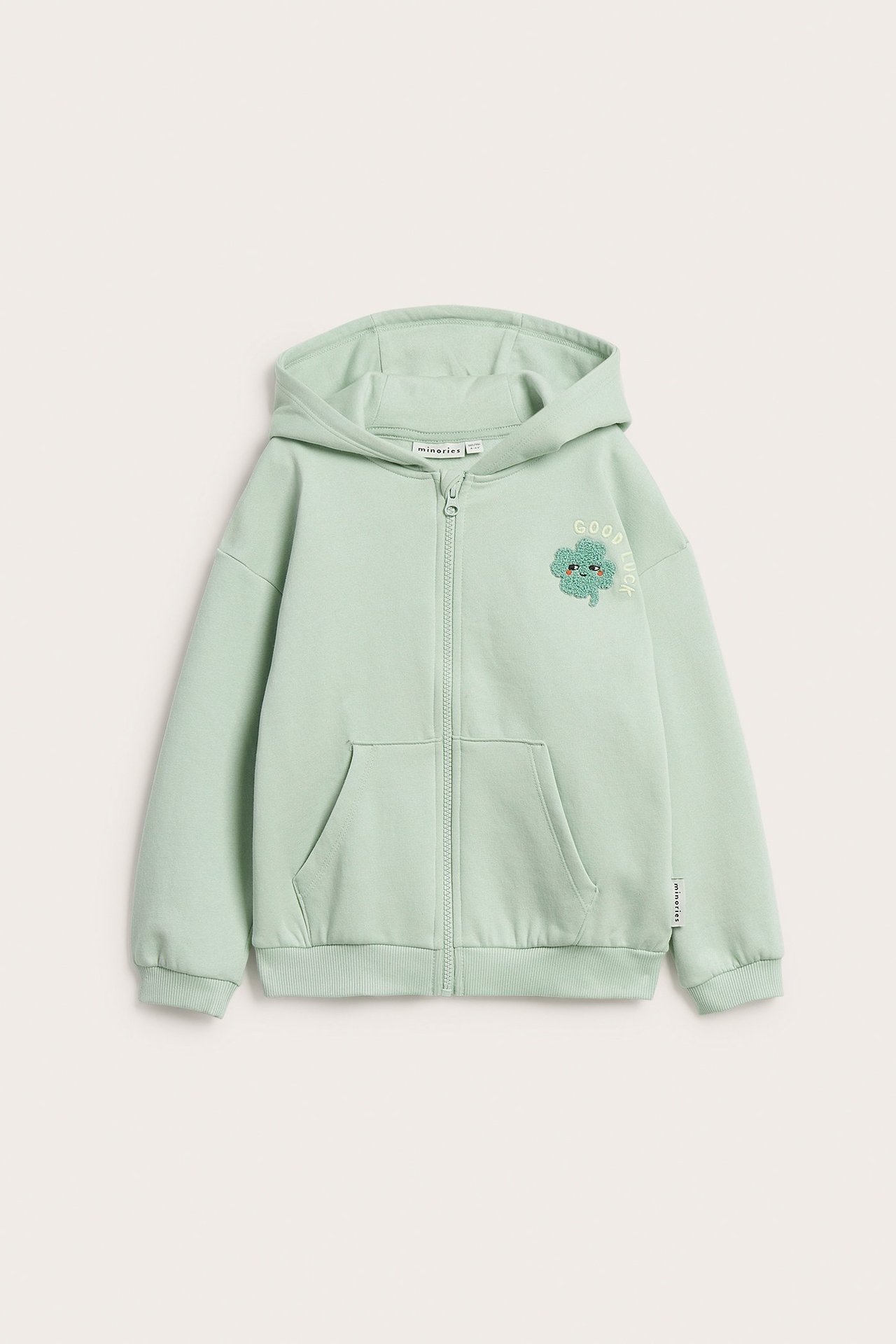 Widok z przodu, dziecięca jasnozielona bluza z kapturem, zamkiem, haftem koniczyny, napisem "GOOD LUCK" i kieszeniami.