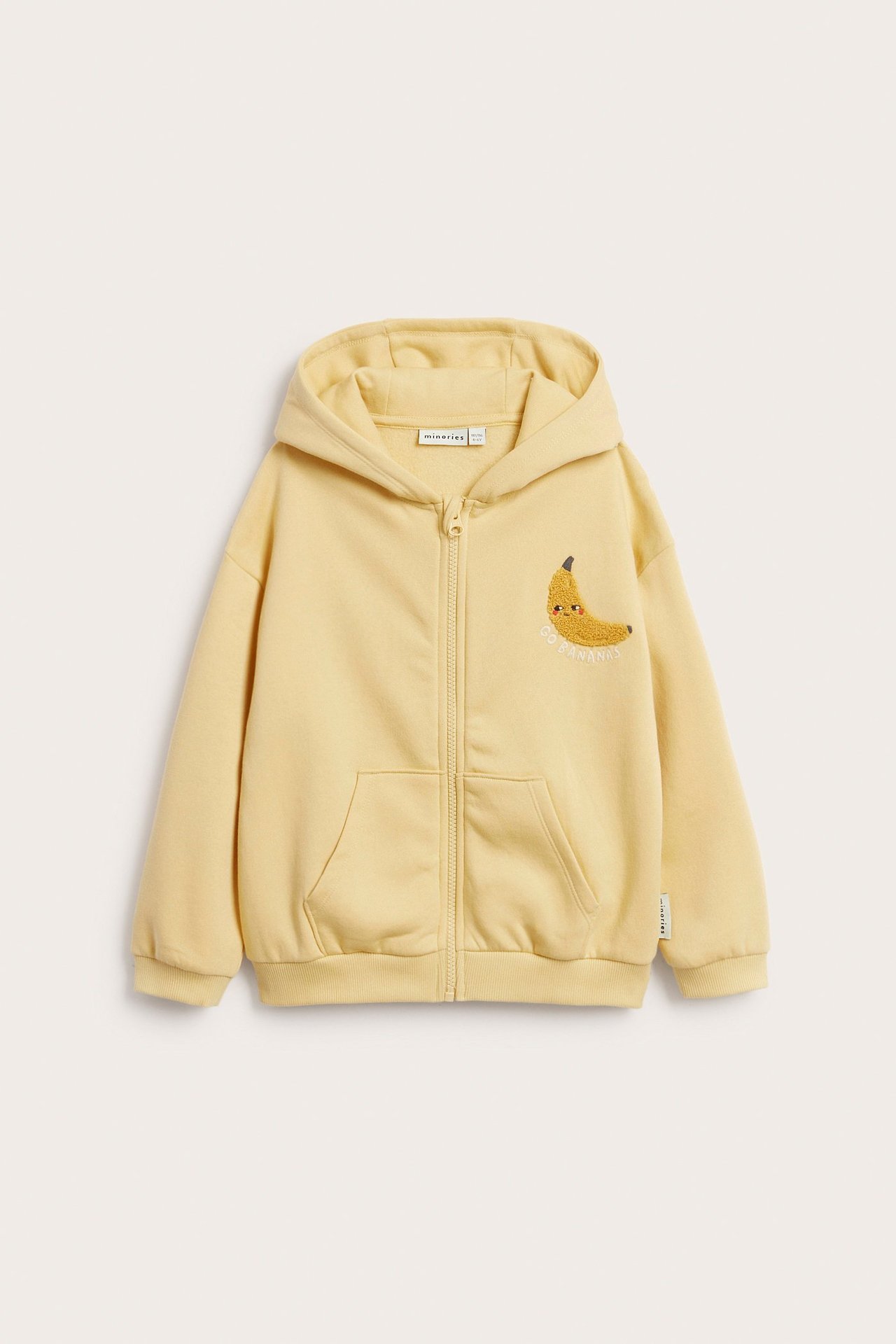 Widok z przodu żółtej bluzy dziecięcej z kapturem, zamkiem, przednimi kieszeniami i haftem banana.