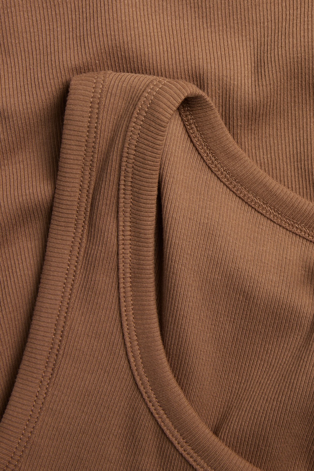 Nærbilde av en brun ribbestrikket topp med smal struktur.