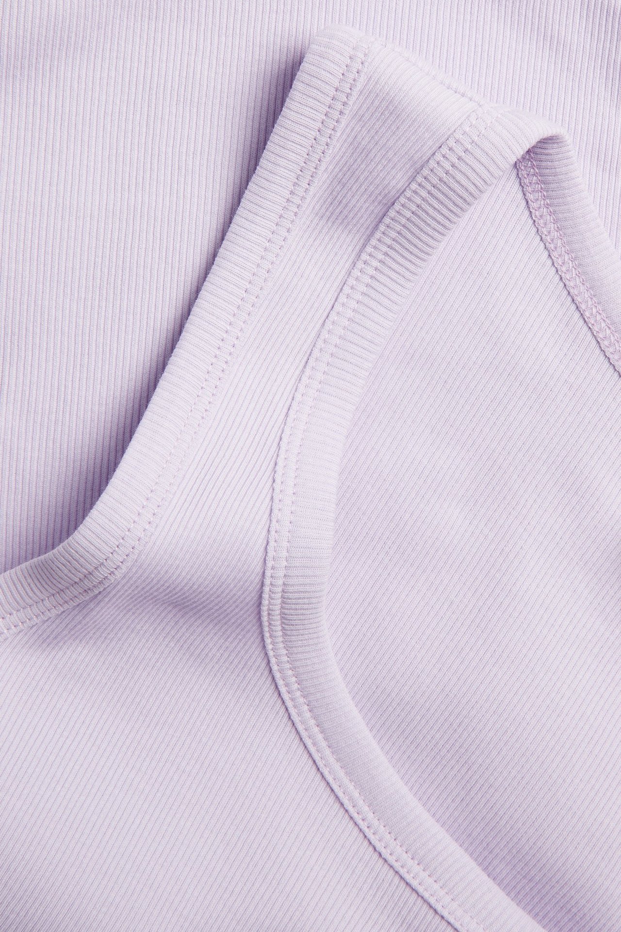 Zbliżenie na jasnoliliowy top w prążki, ukazujące teksturę materiału i szwy.