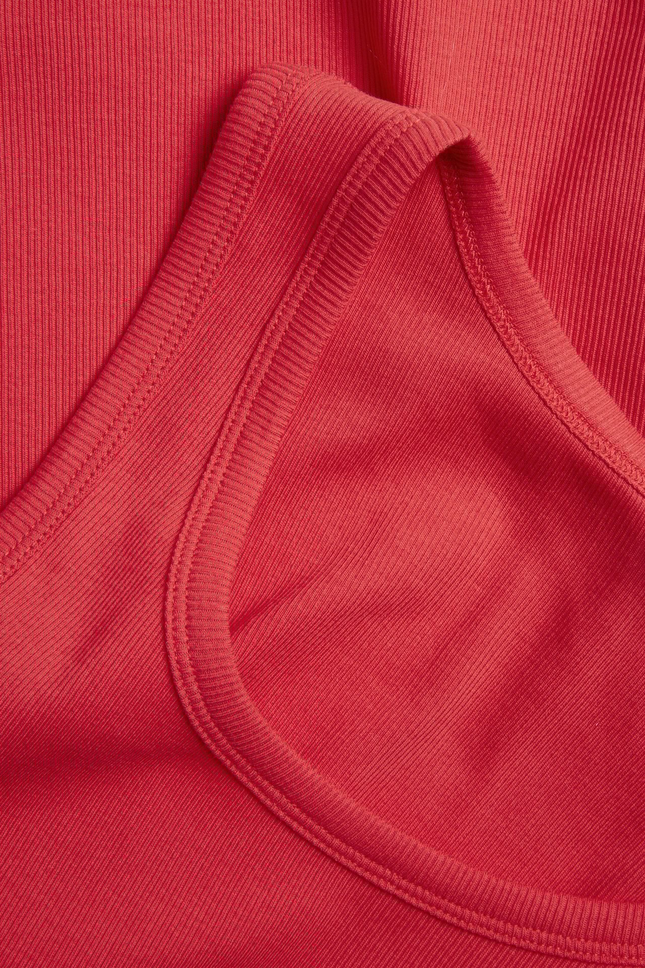 Lähikuva punaisesta ribatusta topista, joka esittelee sen kapeaa rakennetta ja pääntietä.