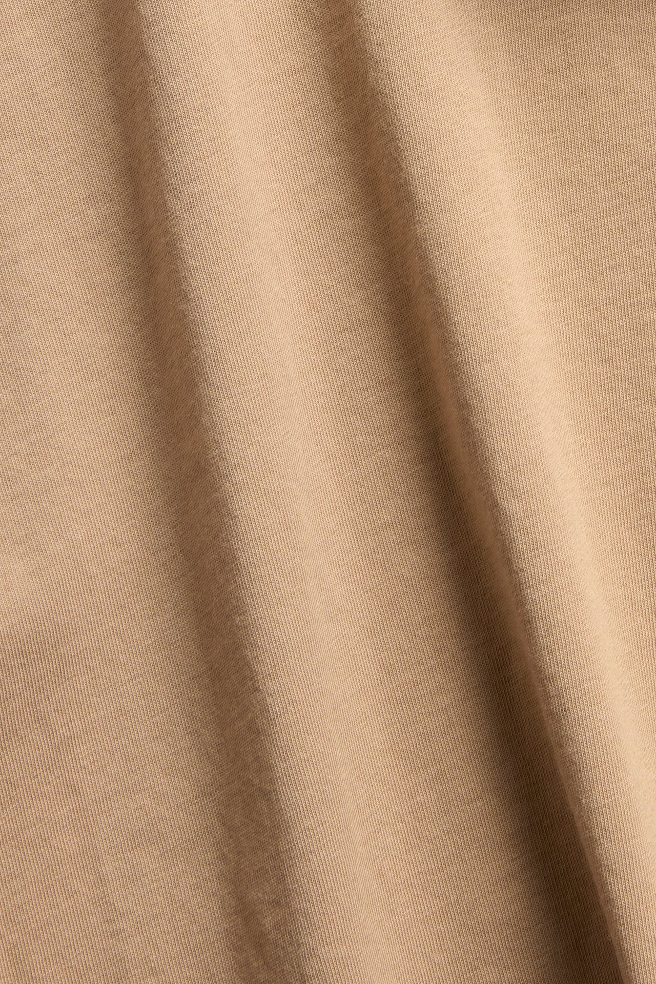 Lähikuva beigestä puuvilla-elastaanineulekankaasta yksivärisestä lyhythihaisesta perustopista.