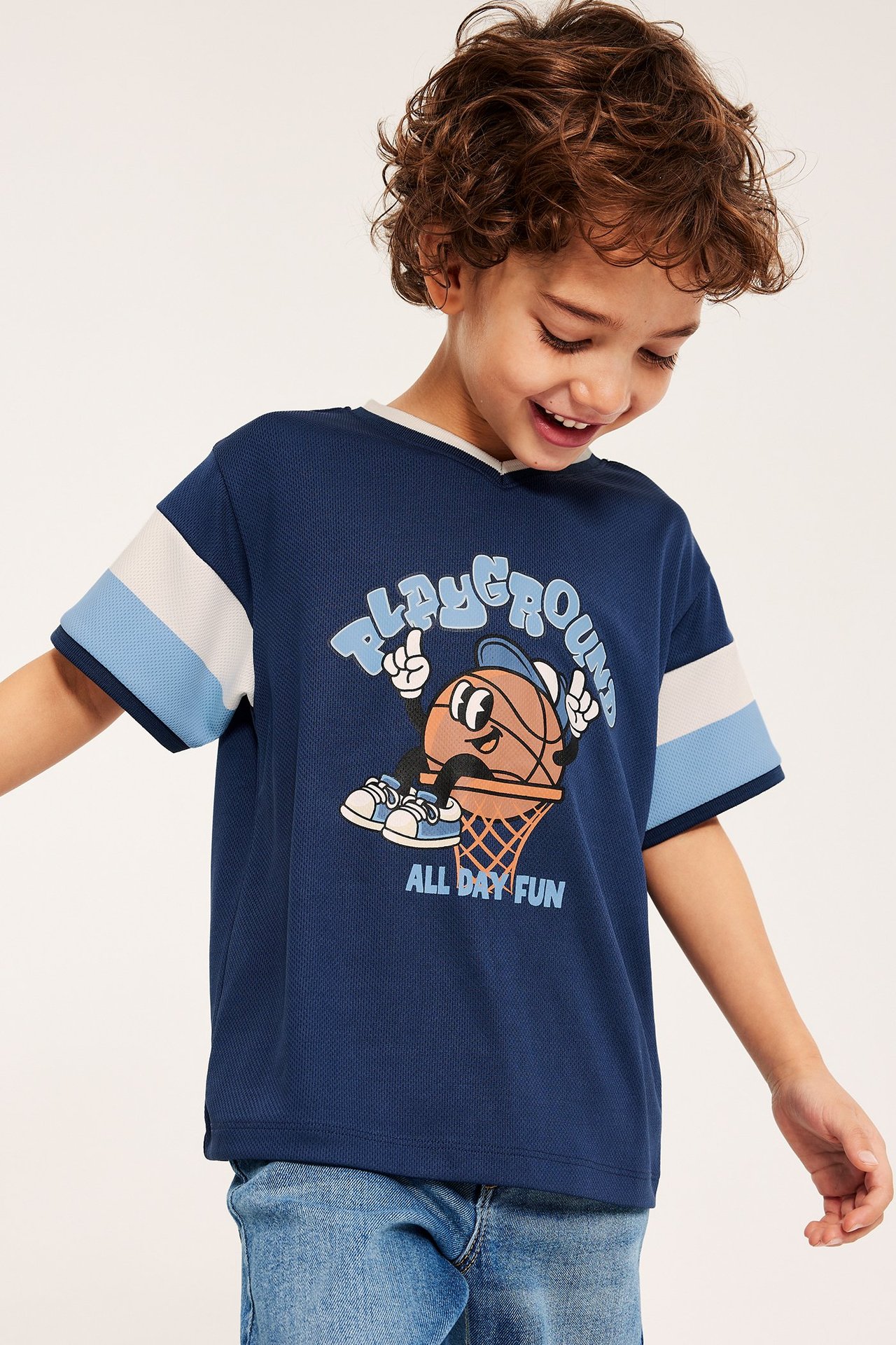 Widok z przodu: Dziecko w granatowym T-shircie z siateczki, z nadrukiem i rękawami w paski.
