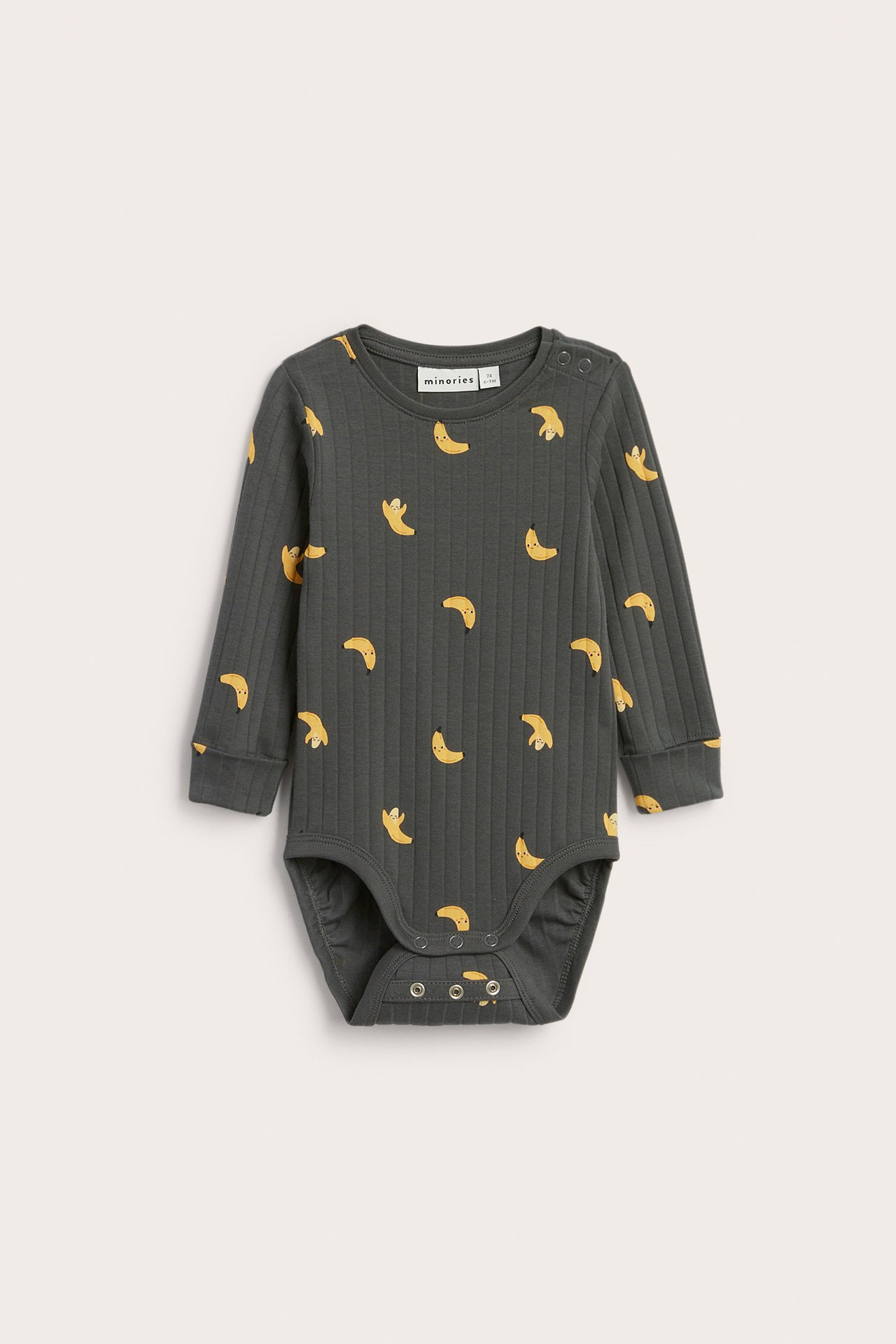 Edestä: vauvan tummanharmaa ribattu pitkähihainen body keltainen banaanikuvio ja nepparit.