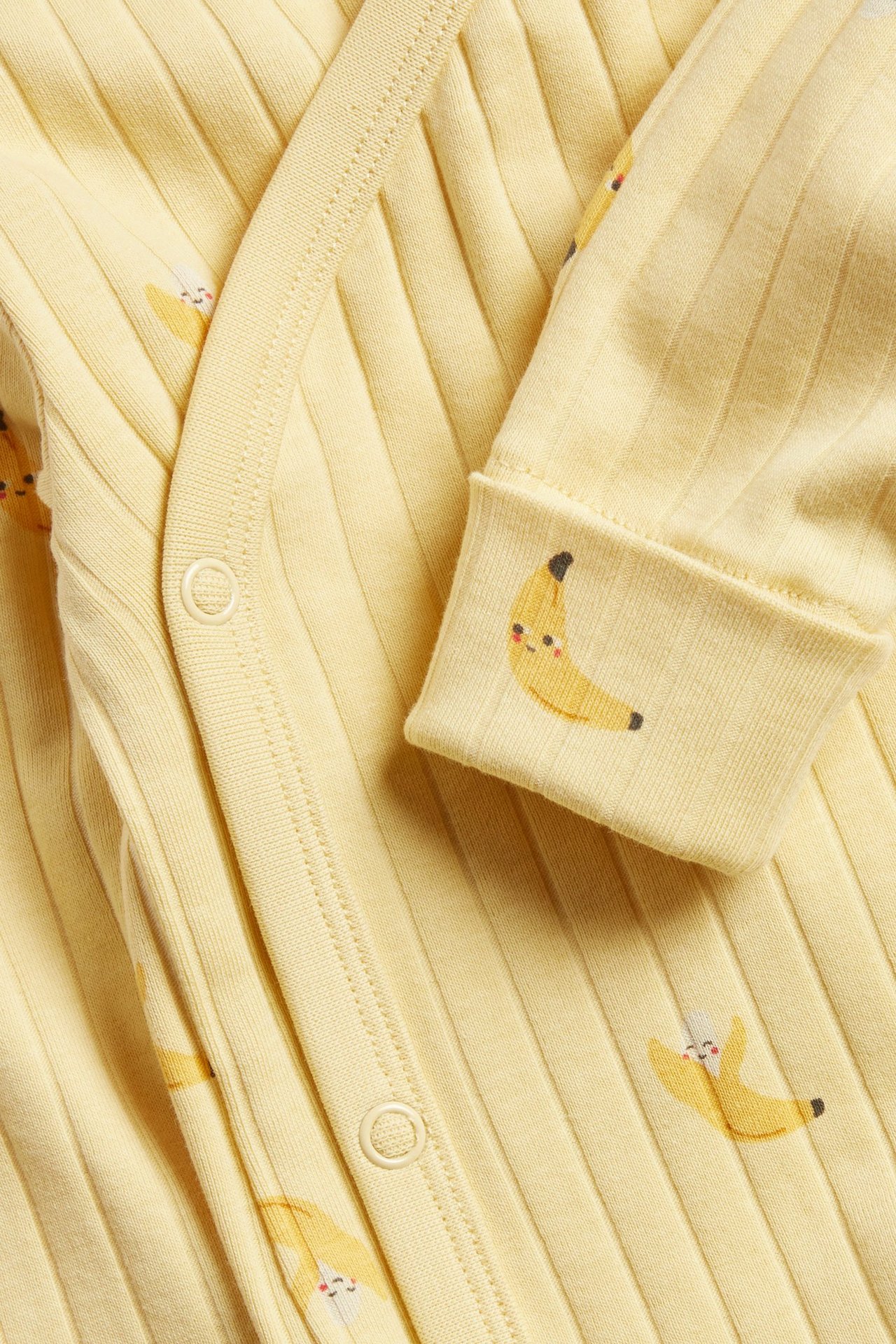 Zbliżenie, widok z przodu: Żółte, prążkowane, długie rękawy body niemowlęce z nadrukiem bananów, zapinane na zatrzaski.