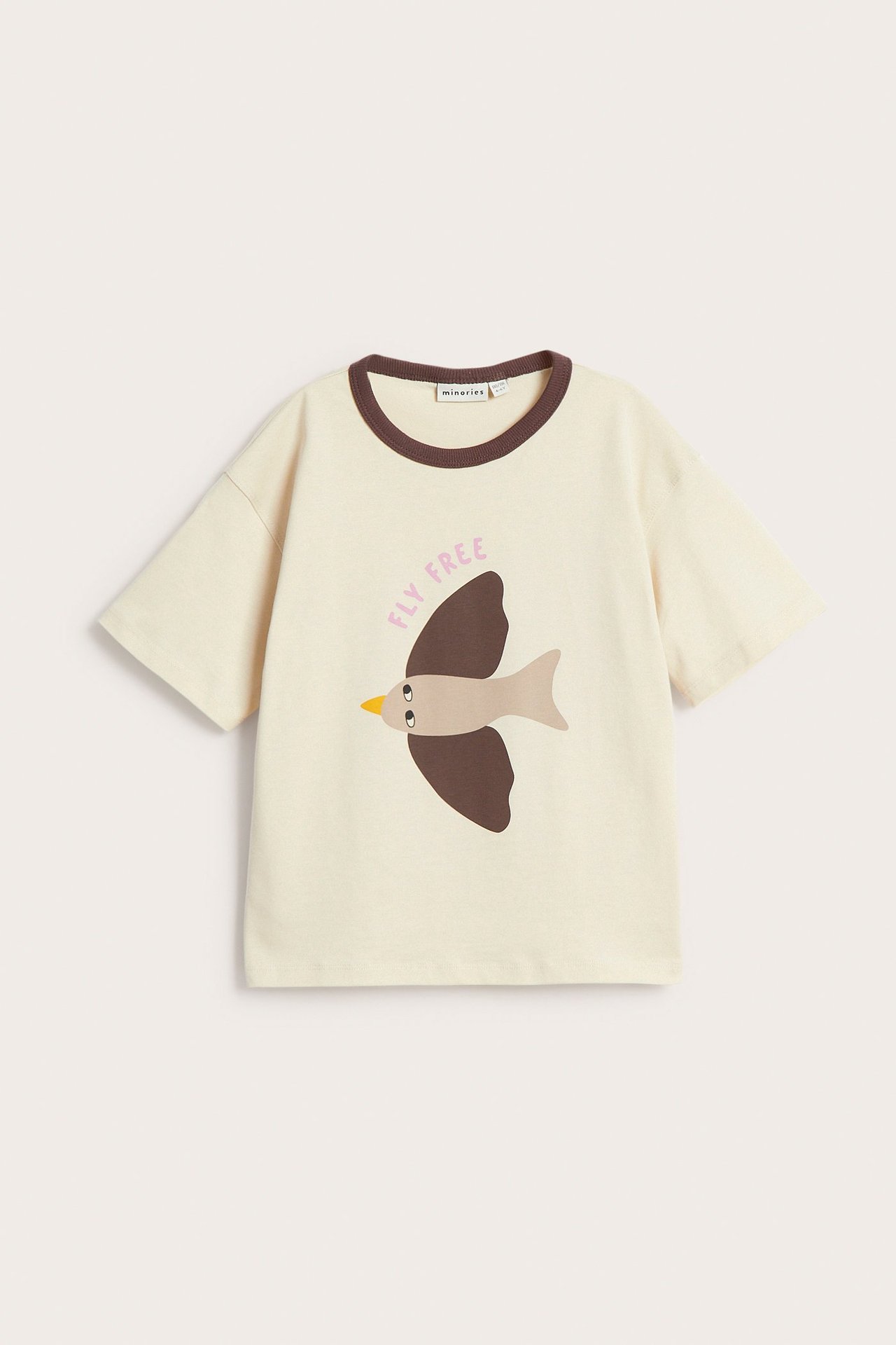 Edestä kuvattu lapsen beige lyhythihainen puuvillainen t-paita ruskealla lintupainatuksella ja "fly free" tekstillä.