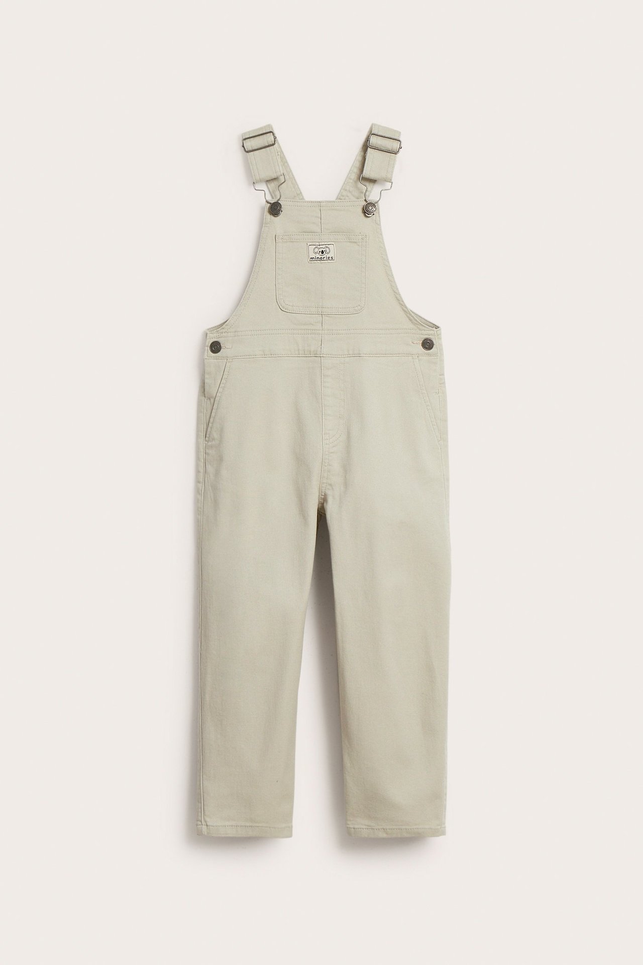 Lasten beiget twill-haalarihousut edestä nähtynä säädettävillä olkaimilla, rintataskulla ja sivunapeilla.