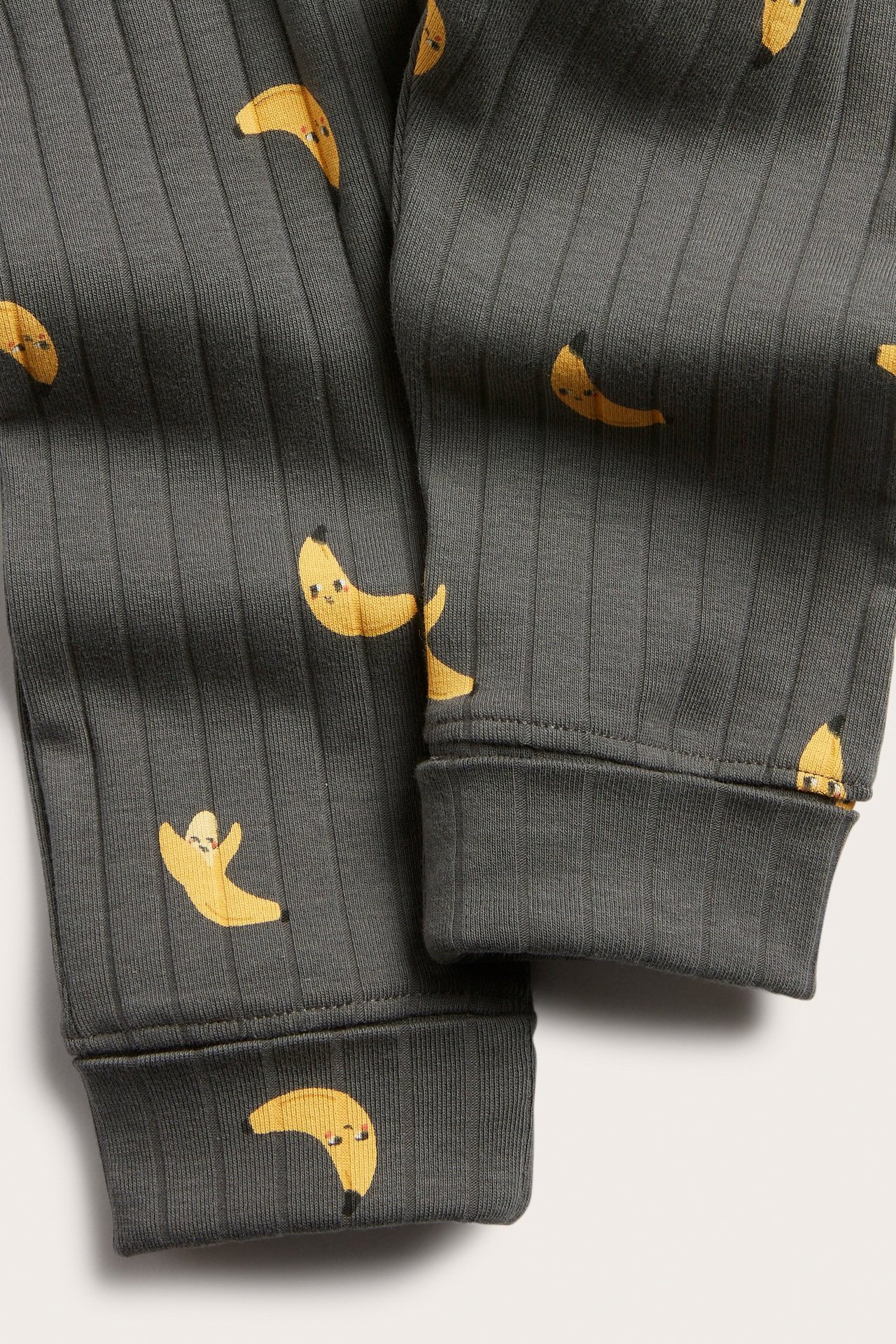 Lähikuva tummanharmaista ribatuista leggingseistä, banaanikuviolla ja taitettavilla resoreilla.