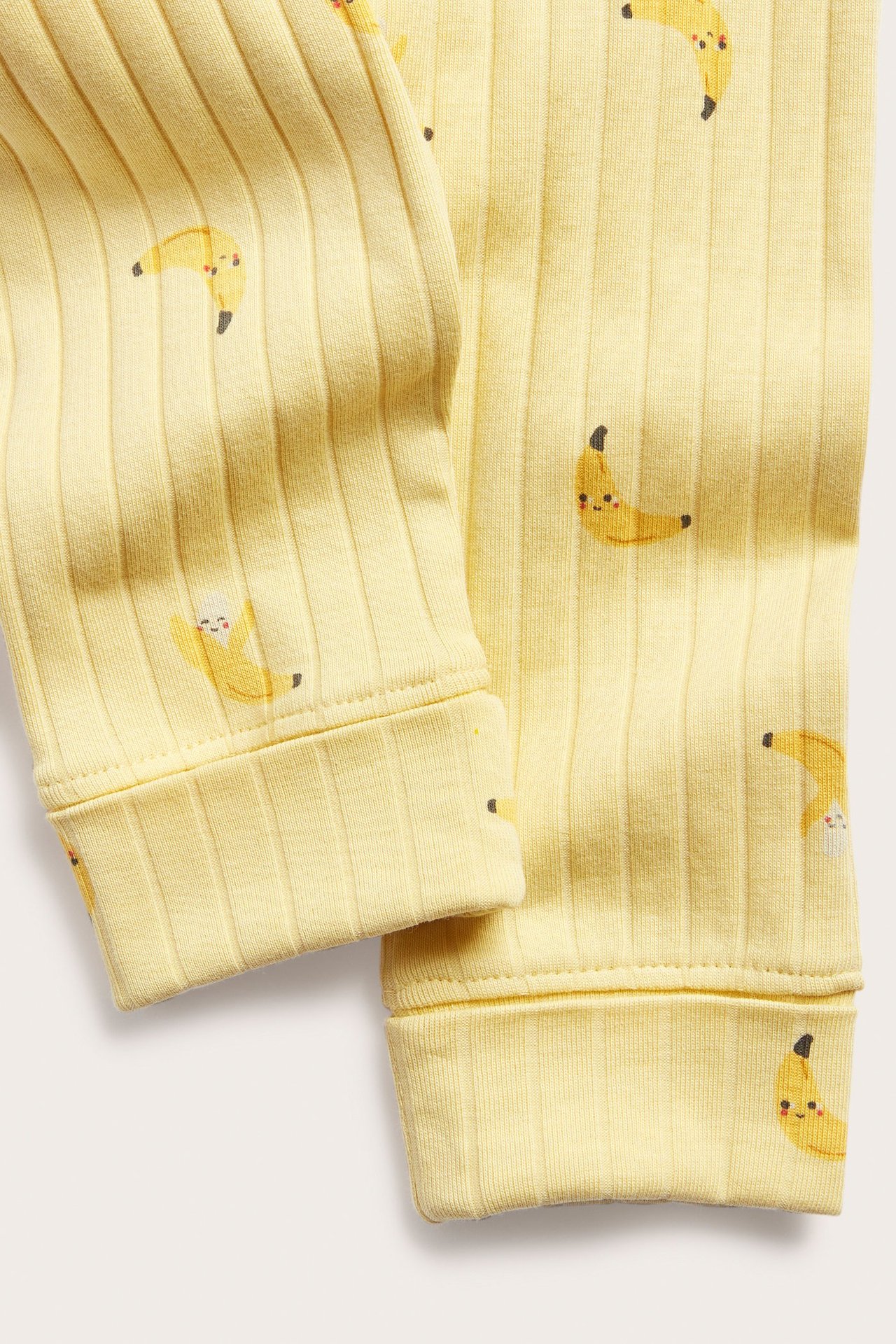 Lähikuva keltaisista ribatuista vauvan leggingseistä, joissa on banaaniprintti ja taitettavat resorit.