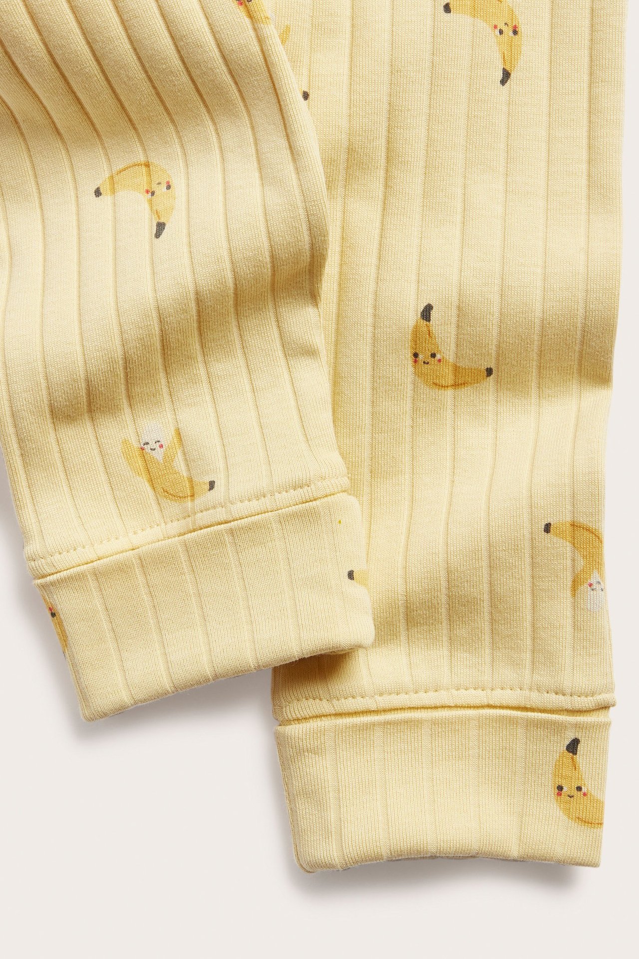 Lähikuva keltaisista ribbatuista vauvan leggingseistä, joissa on banaanikuosi ja taitettavat resorit.