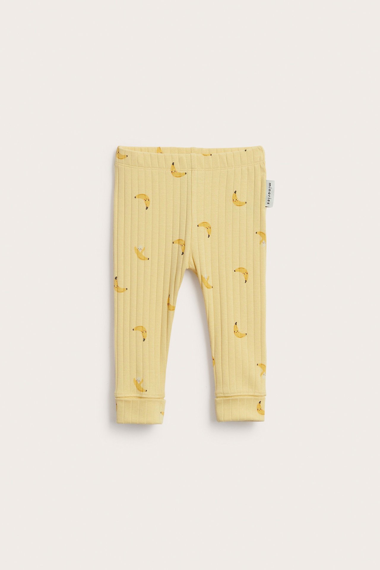 Edestä näkymä vauvan keltaisista ribbileggingseistä, banaanikuvio, joustovyötärö, taitettavat resorit.