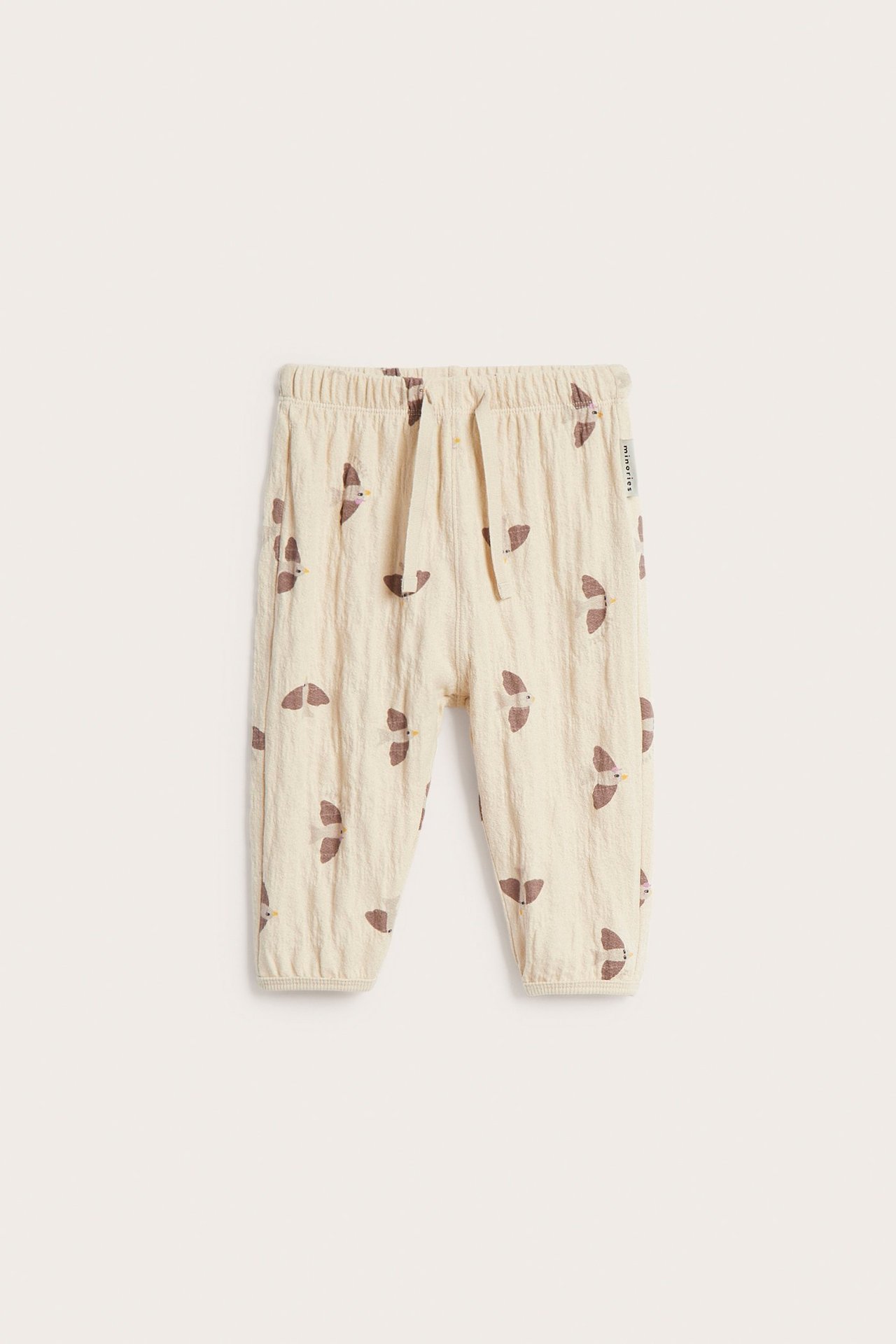 Frontvisning av mønstrete beige babyjoggebukse med brune fugler, elastisk midje og snøring.