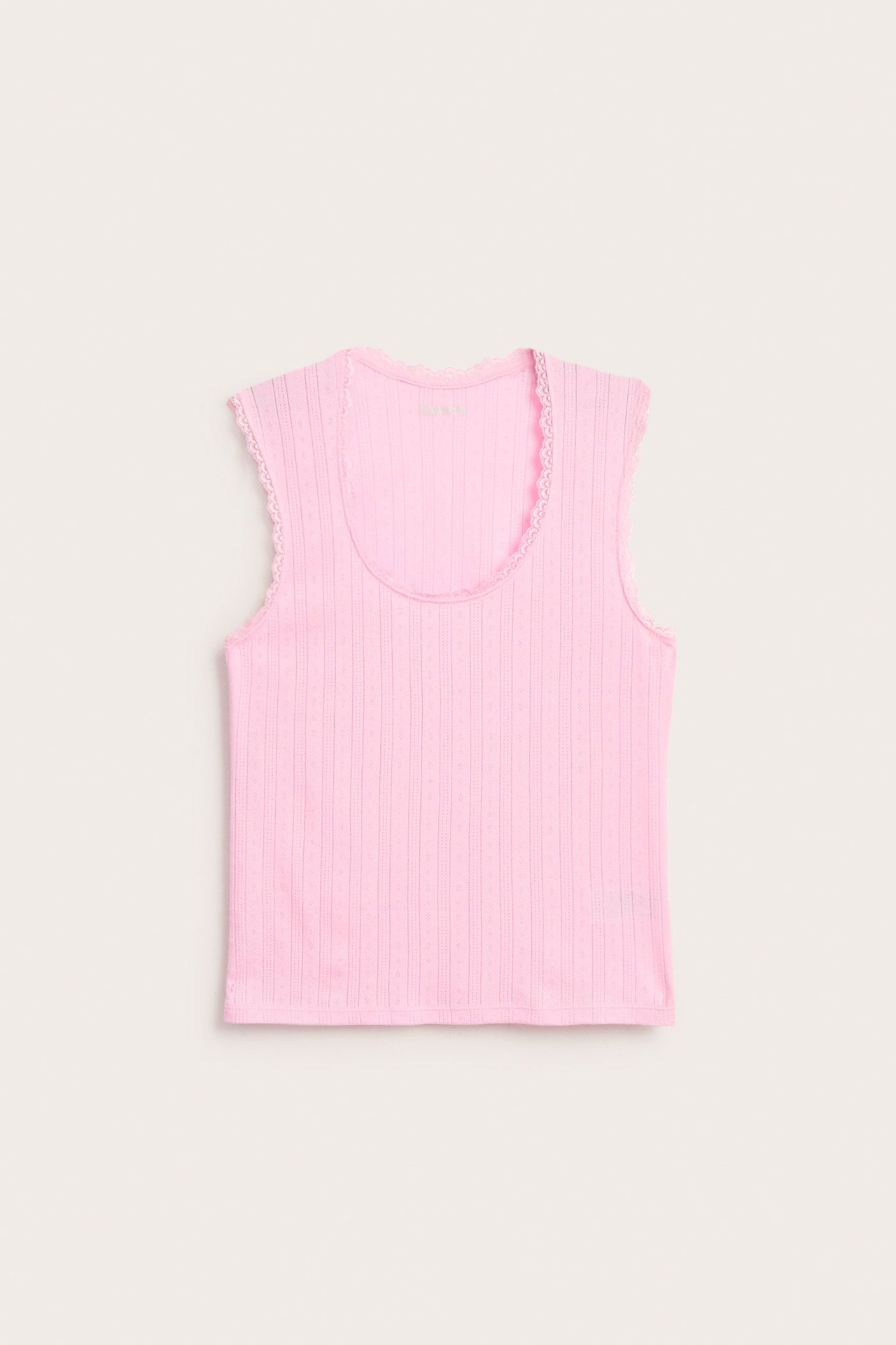 Edestäpäin, vaaleanpunainen pointelle-jerseypyjamatoppi, jossa on ribattu rakenne ja pitsireunat.