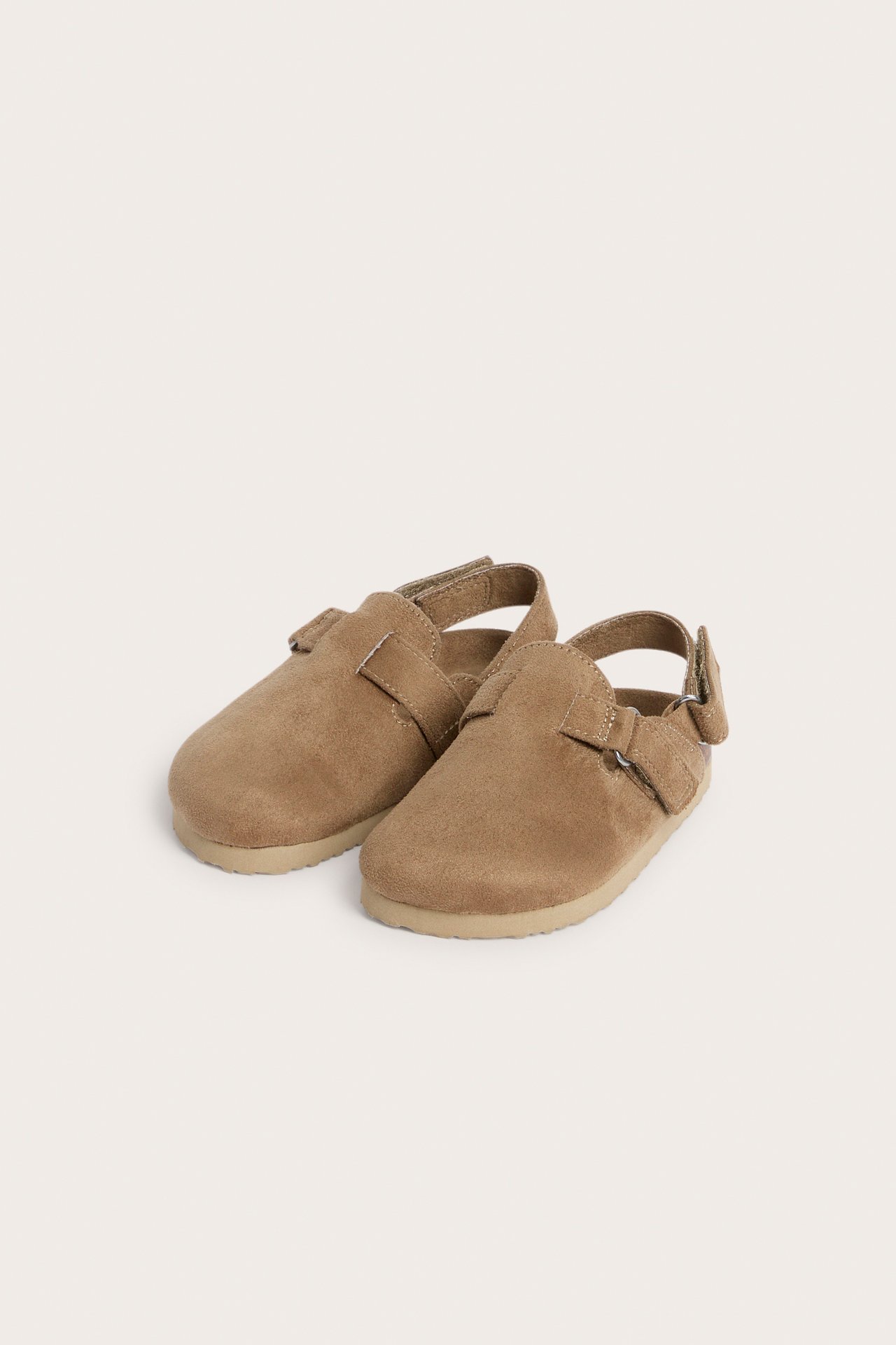 Edestäpäin, lasten beiget mokkajäljitelmätossut tarranauhoilla.