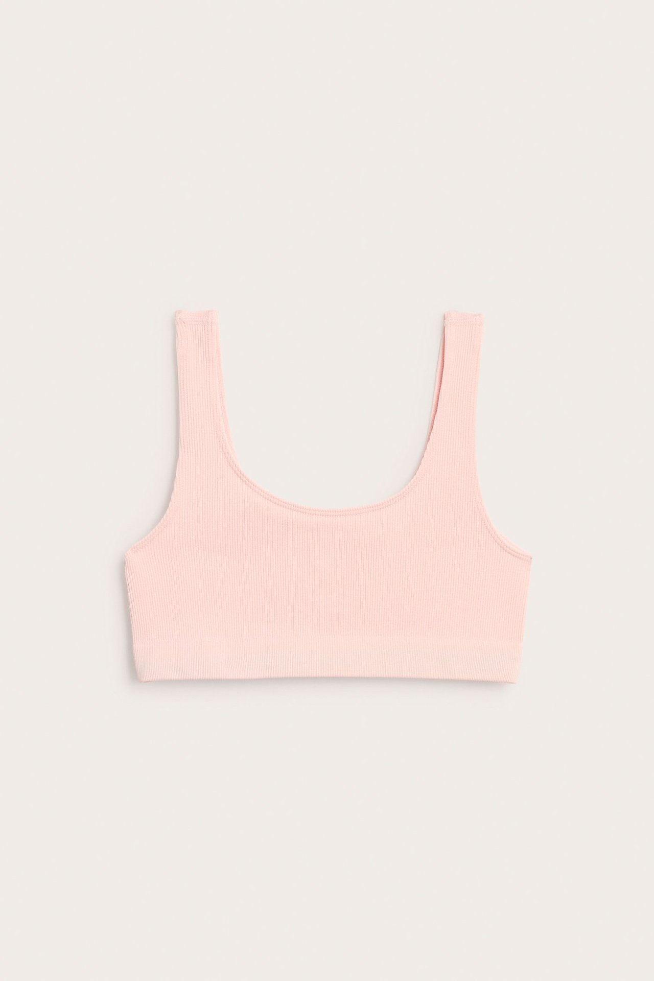 Widok z przodu jasnoróżowego, bezszwowego, prążkowanego topu typu crop z poliamidu i elastanu.