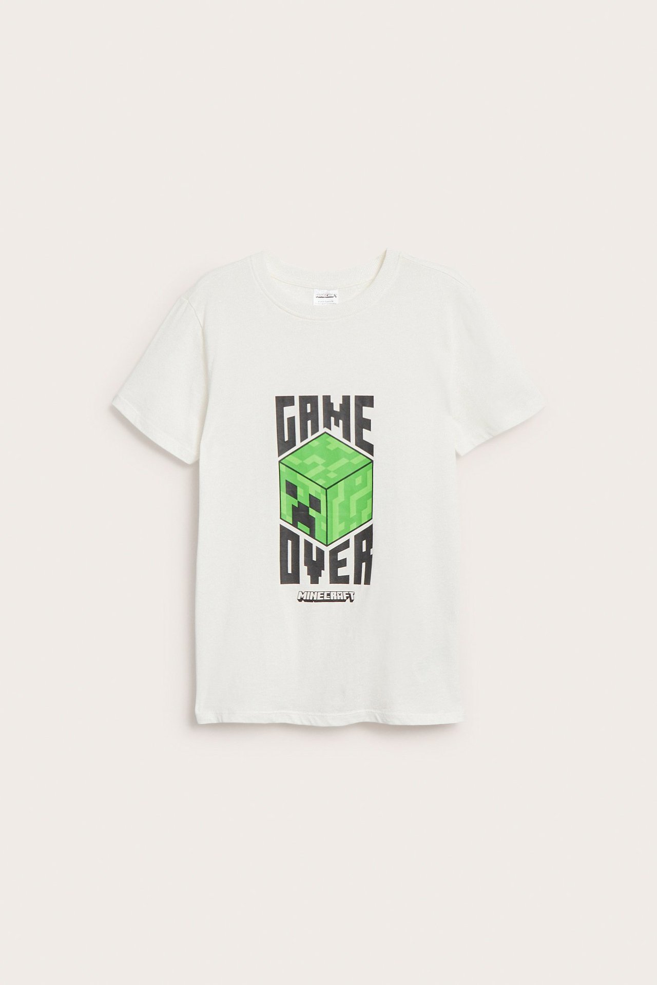 Edestä kuvattu offwhite puuvillainen T-paita vihreällä Minecraft 'Game Over' -painatuksella ja ribbineuloksella.