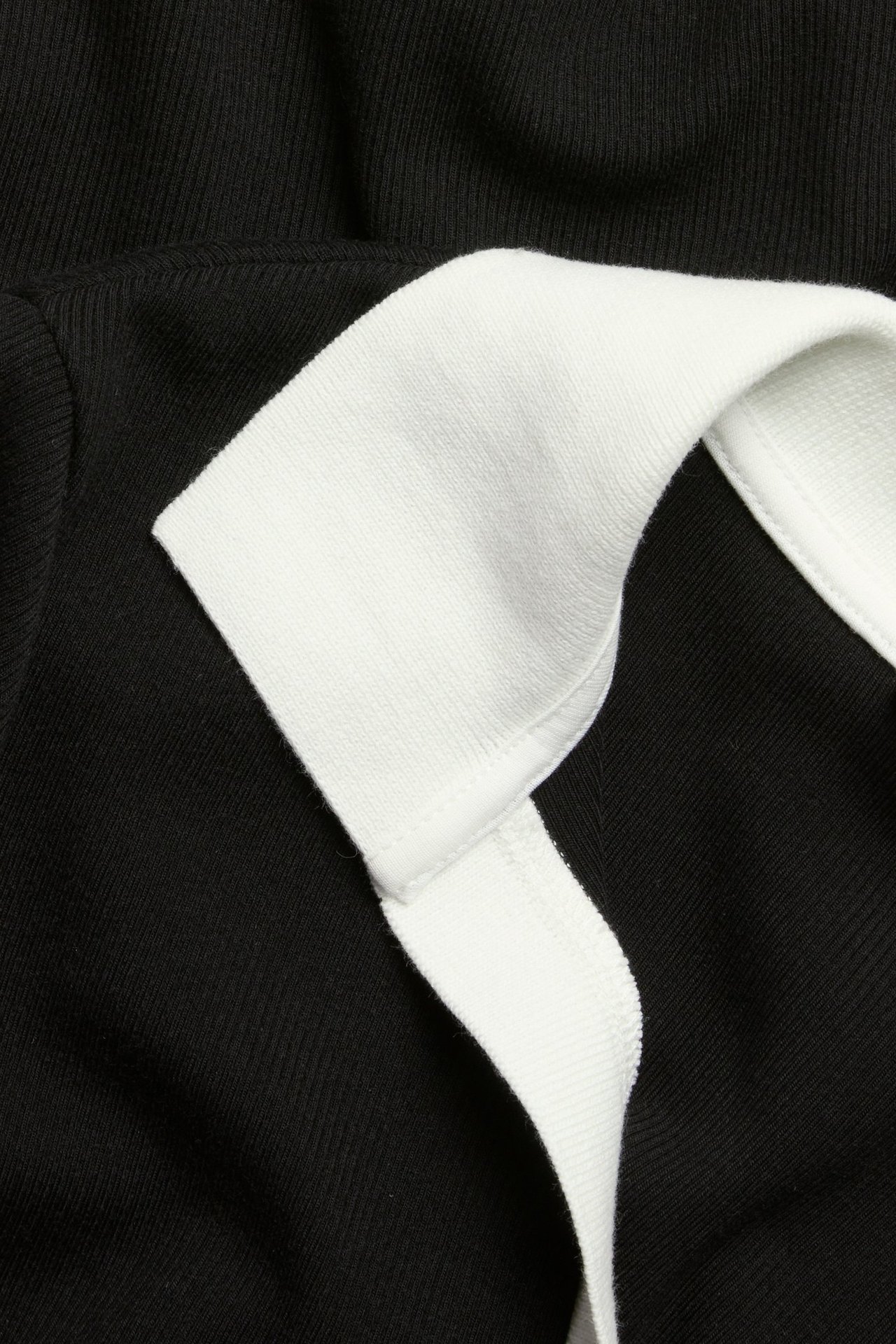 Zbliżenie czarnego topu z krótkim rękawem i kontrastującym białym kołnierzykiem polo.