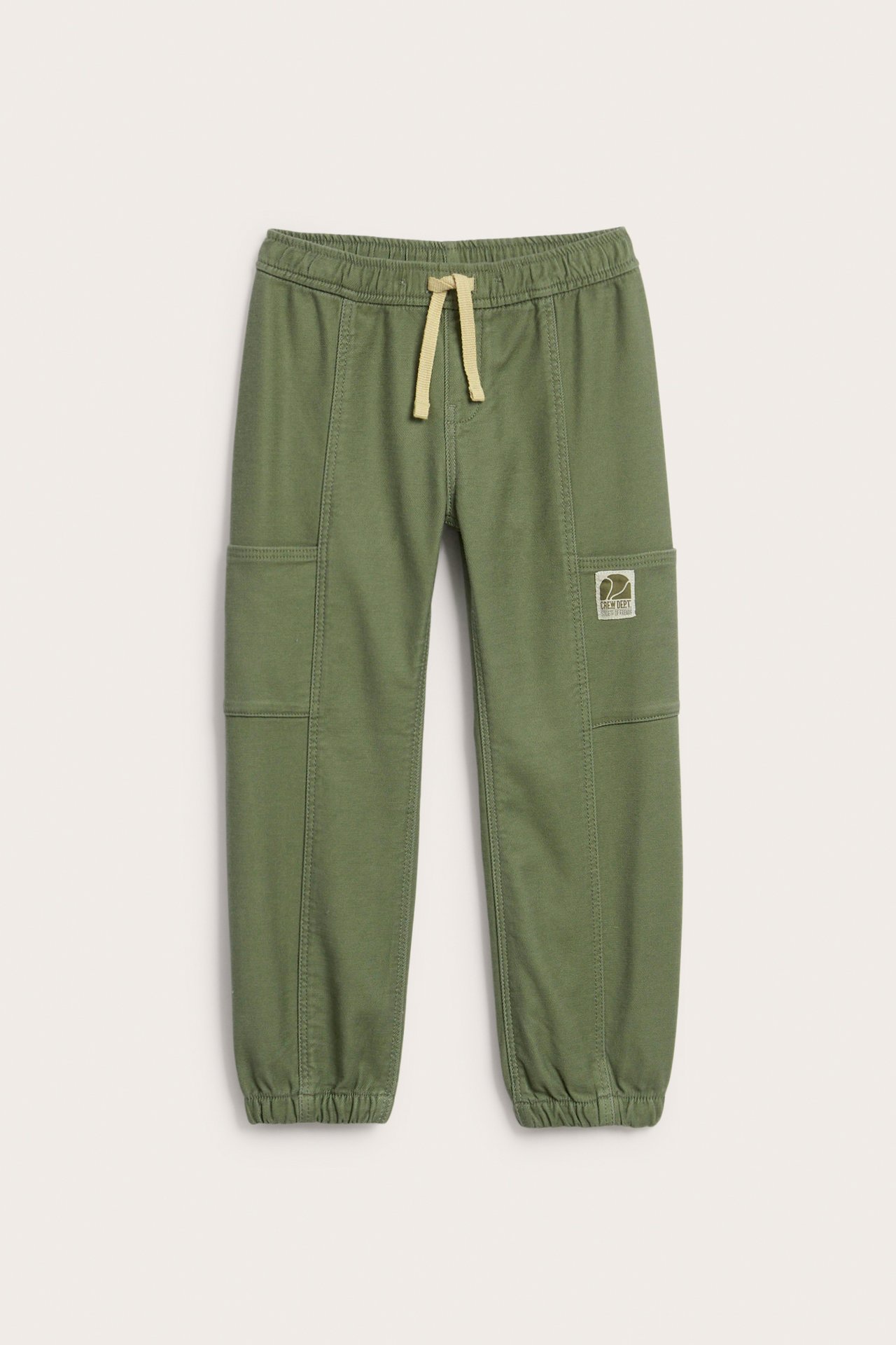 Mørkegrønne joggebukser for barn med strikk i midjen, beige snøring og lommer.