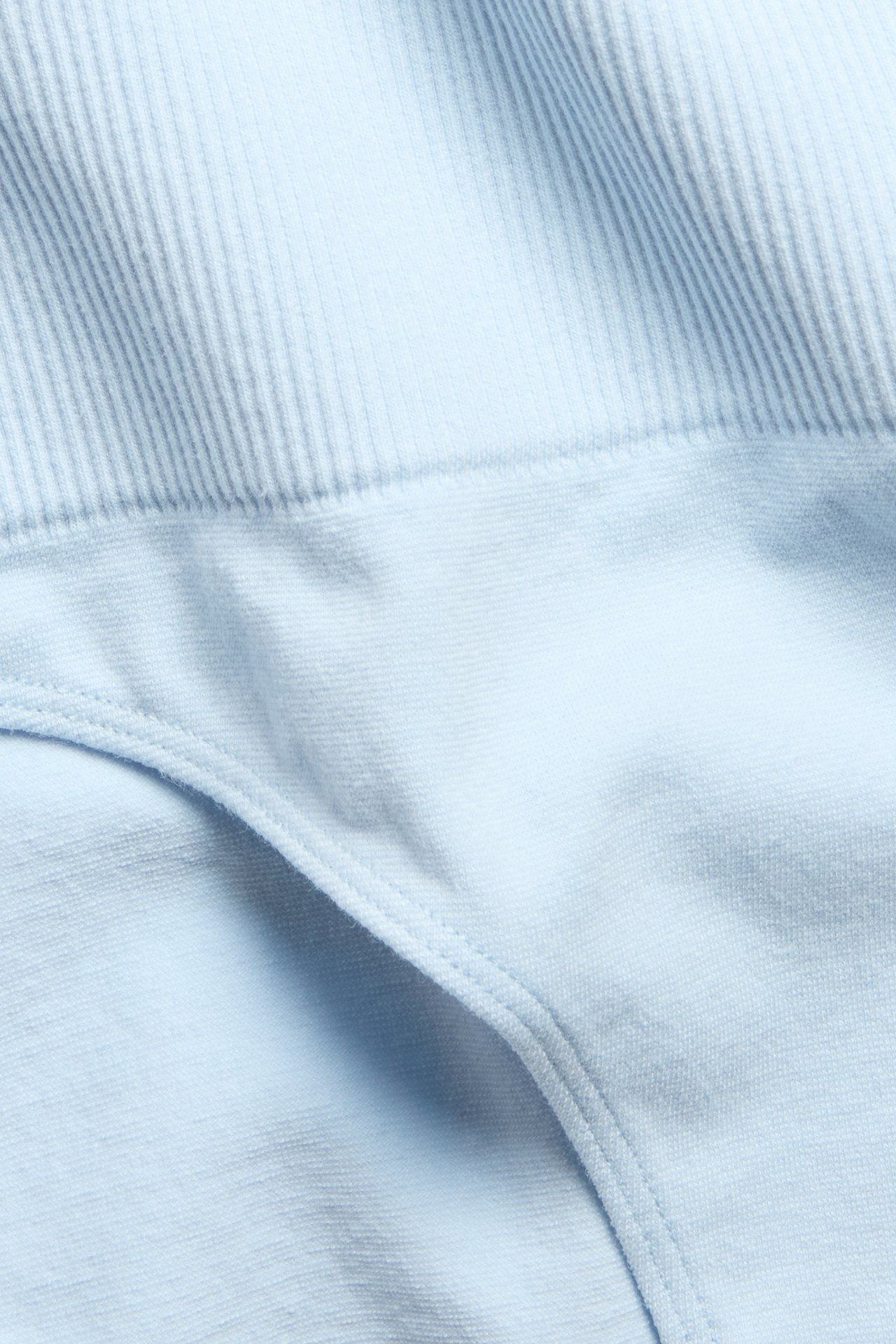 Nærbilde av en lys blå sømløs Brazilian truse med ribbet midje i bomullsmix.