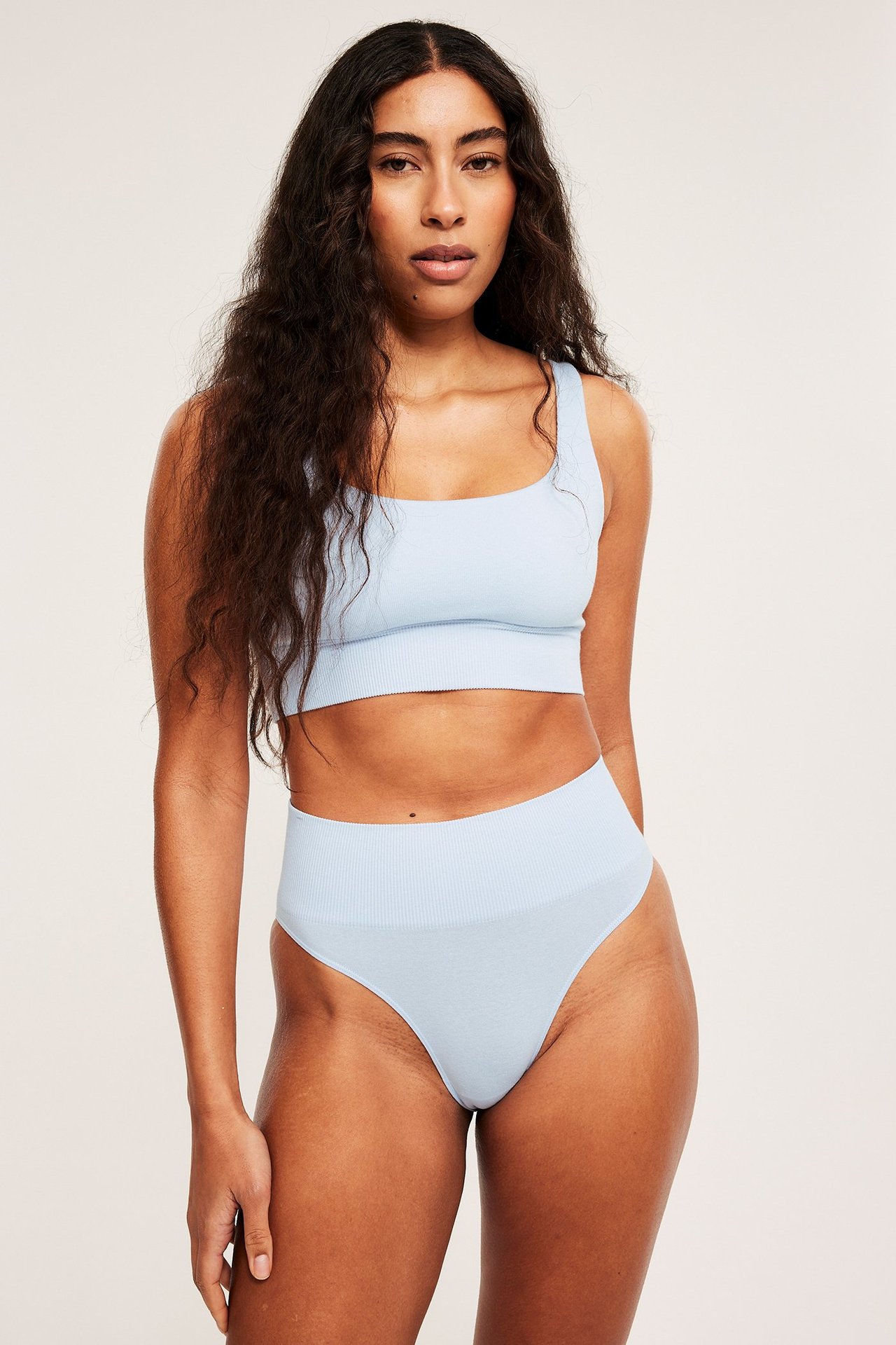 Forfra: Kvinne i lyseblå sømløs Brazilian-truse med ribbet midje og matchende bralette.