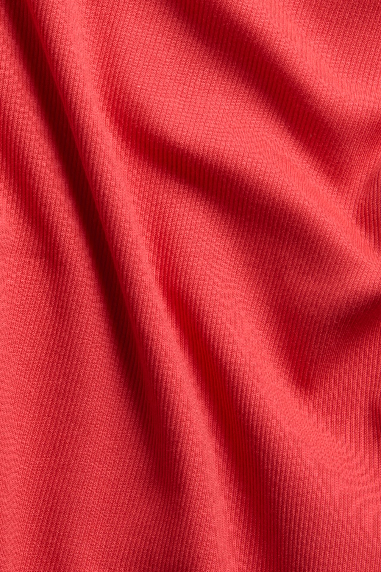 Lähikuva punaisesta ribatusta topin kankaasta, joka näyttää sen pystysuoran rakenteen.