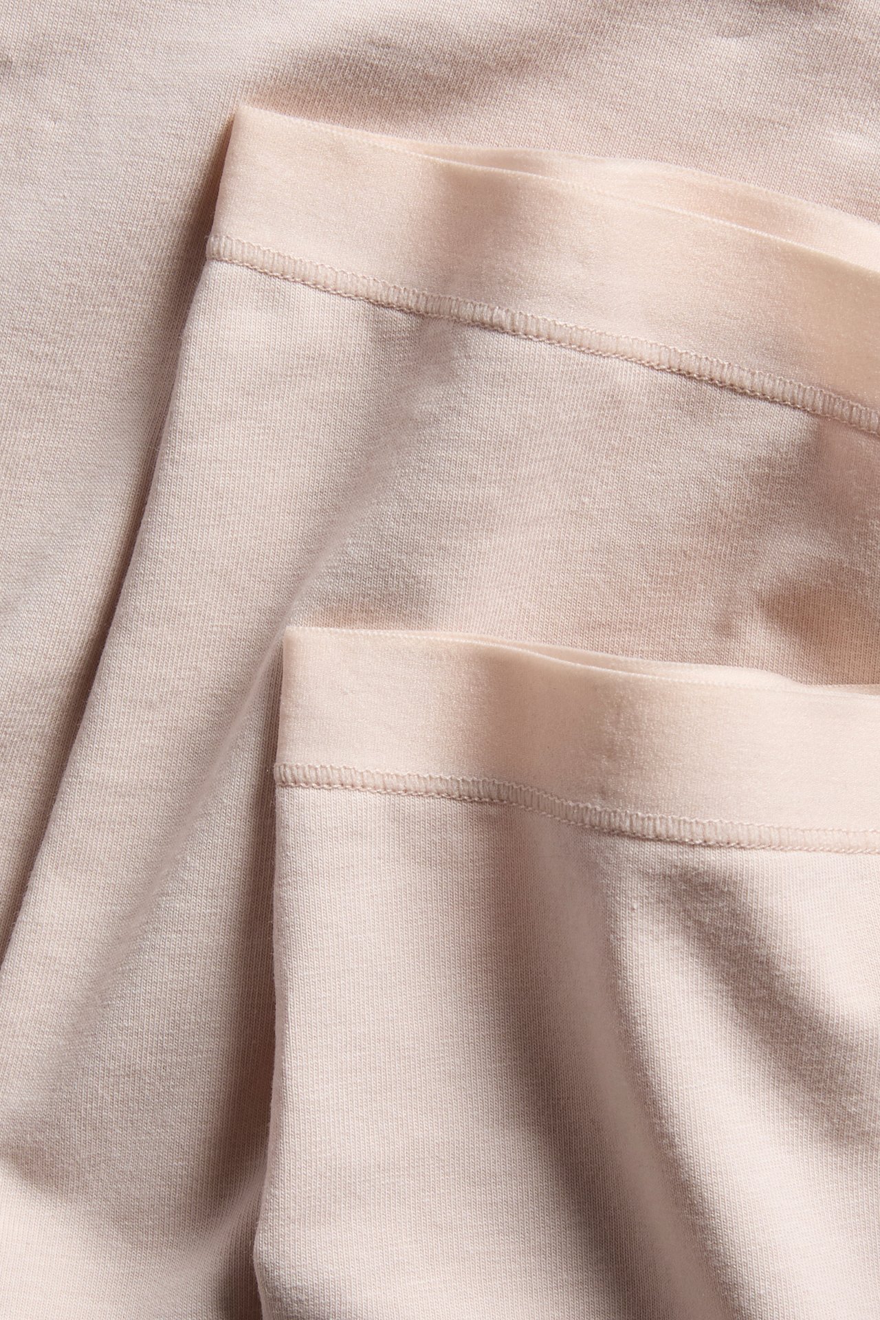 Närbild på vikta ljusrosa enfärgade bomullsboxertrosor, som visar sömmar.