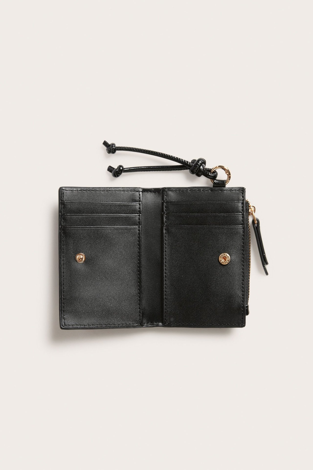 Toppvisning: Åpen svart kortholder i imitert skinn med kortspor, gulltrykknapp, glidelås og knyttet snor.