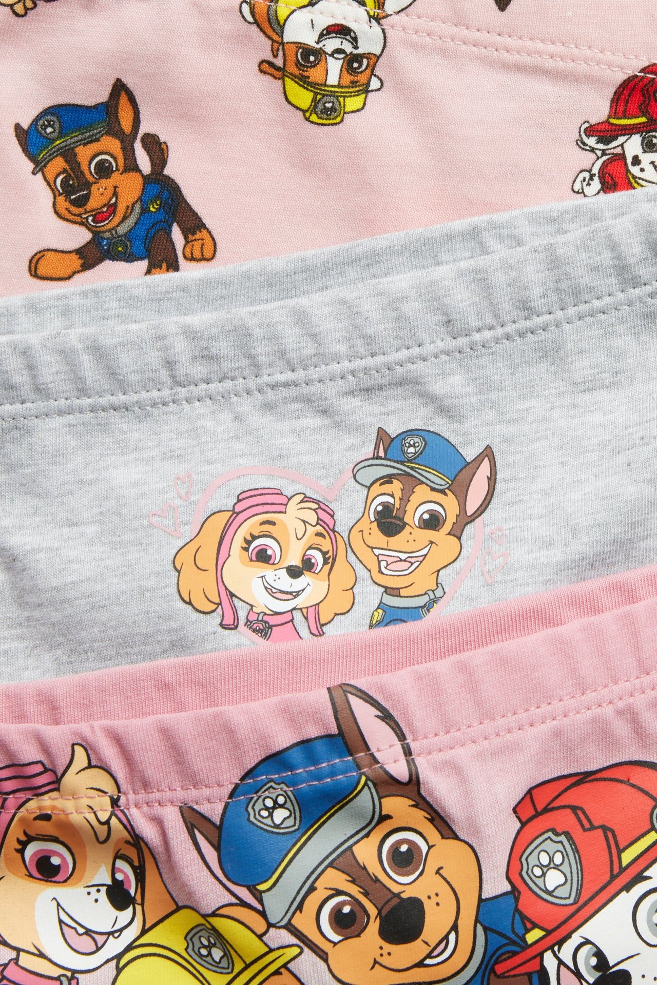 Nærbilde av tre barnboxertruser: to rosa, en grå, alle med Paw Patrol-trykk.